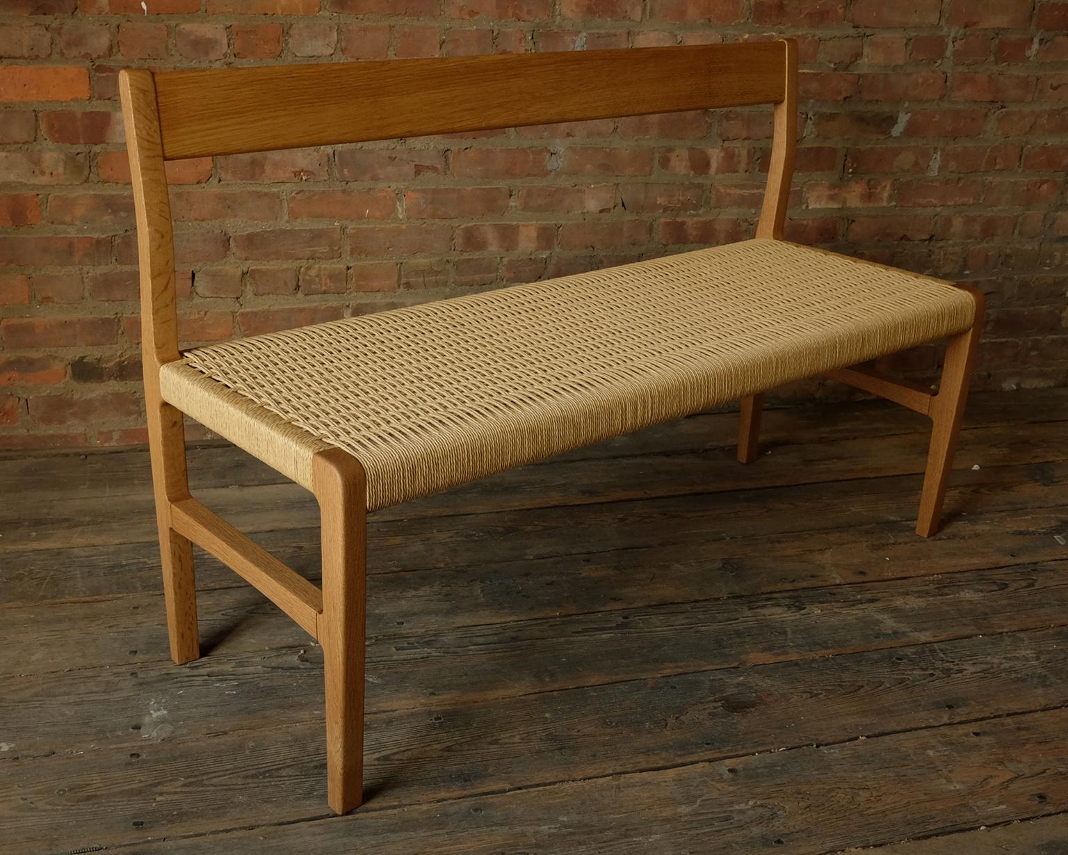 A bench with subtle curves in solid white oak with woven Danish cord seat 48