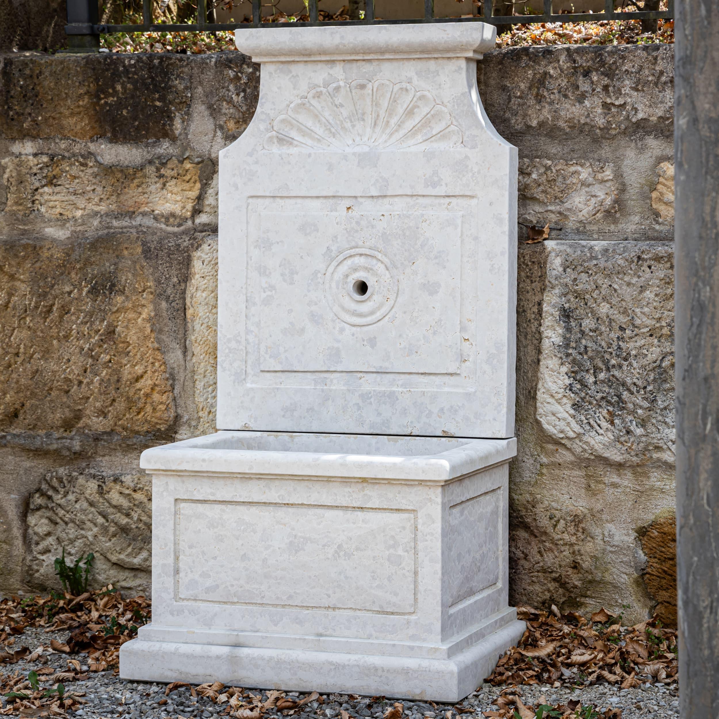 Fuente mural de piedra natural Giallo d'Istria con pila rectangular y trasera de líneas rectas. La sutil ornamentación de la concha y los bordes limpios acentúan la discreta elegancia y la estabilidad.