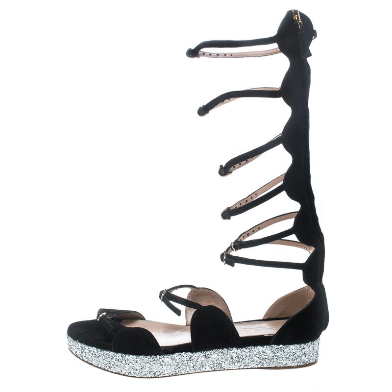 Catch everyone's glances with these gladiator sandals from Giambattista Valli. They've been crafted from suede and styled with buckle straps, back zippers and glitter platforms. They'll look great with chic outfits.

Includes: Packaging