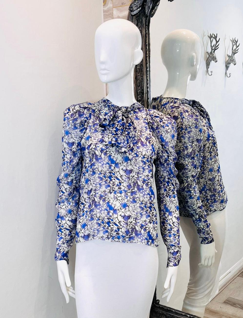 Giambattista Valli Silk Tie-Neck Floral Top

Long sleeved blouse detailed with tiny white and purple floral design.

Featuring tie-neckline, gathered accent to the shoulders and concealed zip fastening to rear.

Size – 38IT

Condition –