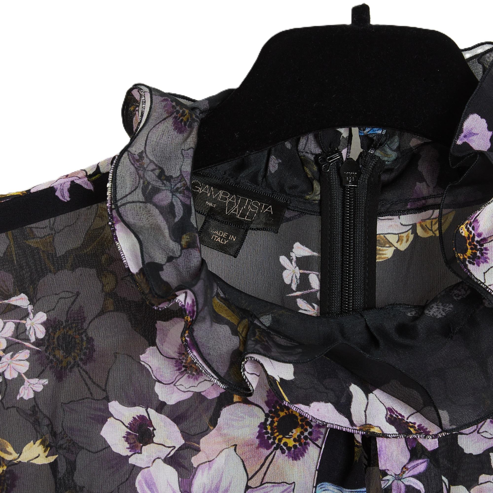 Top Giambattista Valli blouse en mousseline de soie noire à imprimé floral (roses de Noël et libellules) dans les tons rose violet, col rond orné d'un petit volant et d'un petit nœud de chatte, manches longues resserrées par un élastique au poignet,