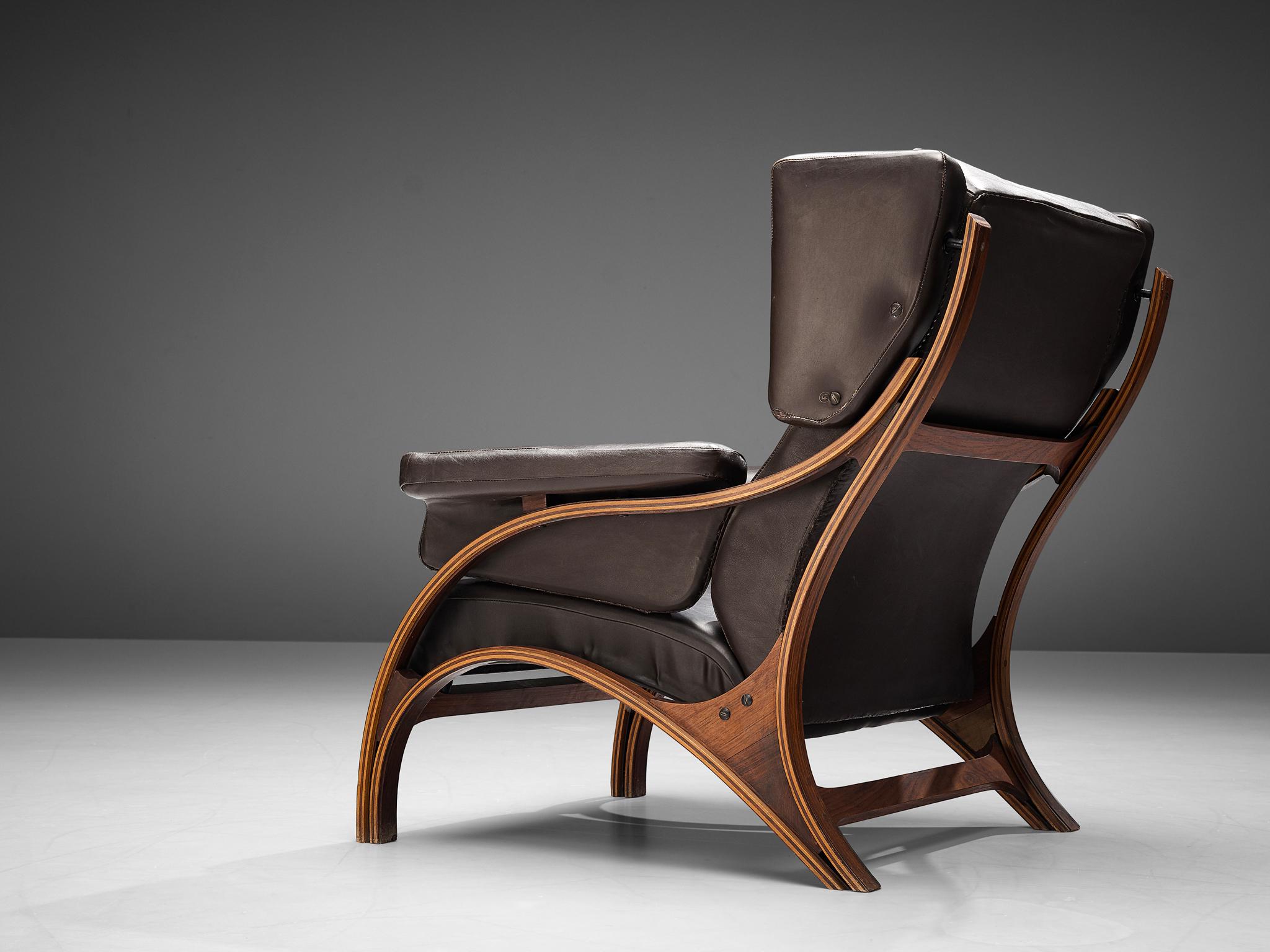 Giampiero Vitelli, lounge chair, plywood, wood, dark brown leather, Italy, 1960s

Eye-catching Italian wingback chair that features curves and gracious forms by Giampiero Vitelli. The most interesting feature is the wooden frame with its fluid