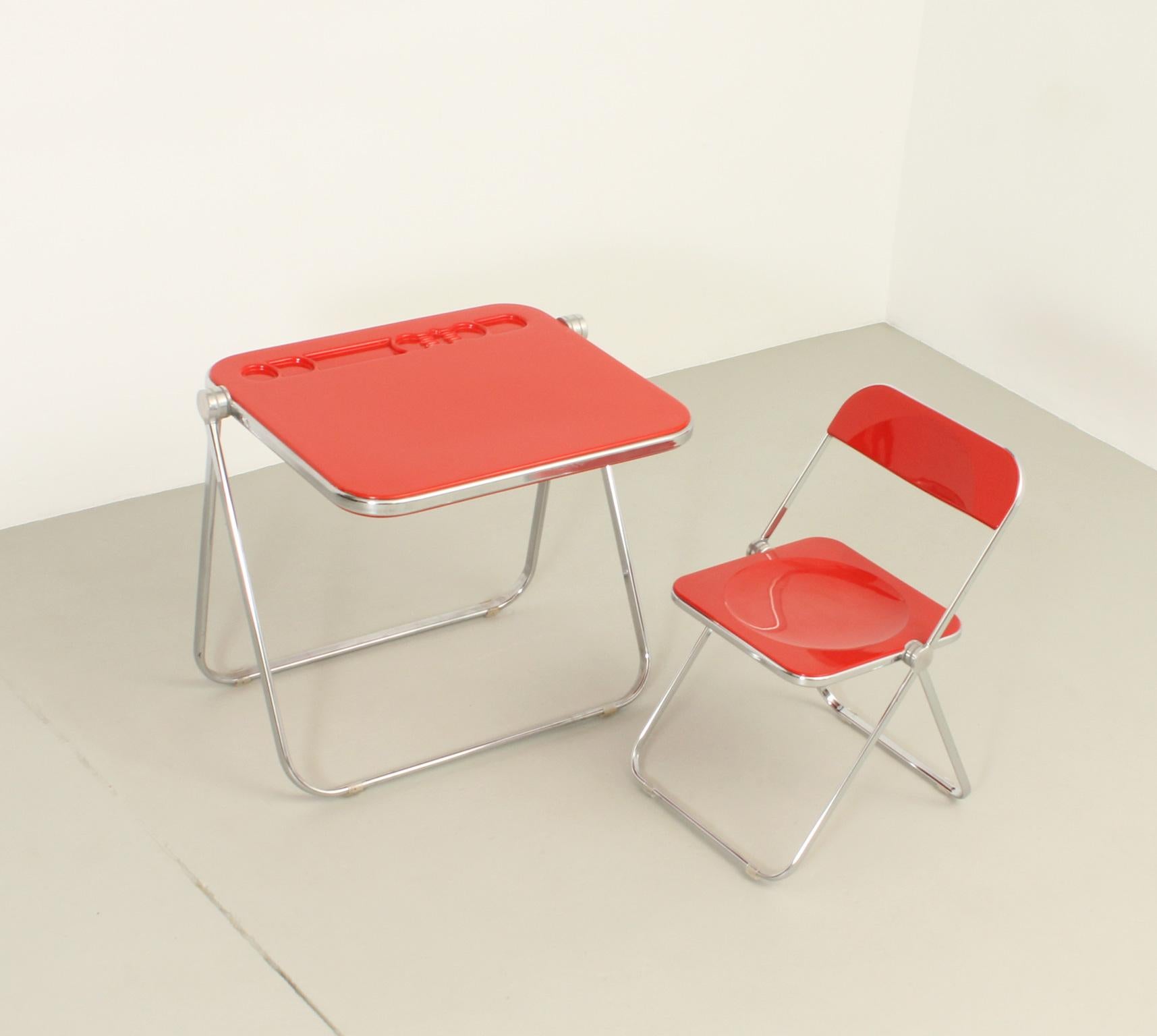 Bureau pliant Platone et chaise Plia conçus en 1971 et 1969 par Giancarlo Piretti pour Anonima Castelli, Italie. Structure articulée en acier chromé avec plastique moulé ABS rouge. Édition ancienne avec label en papier. 