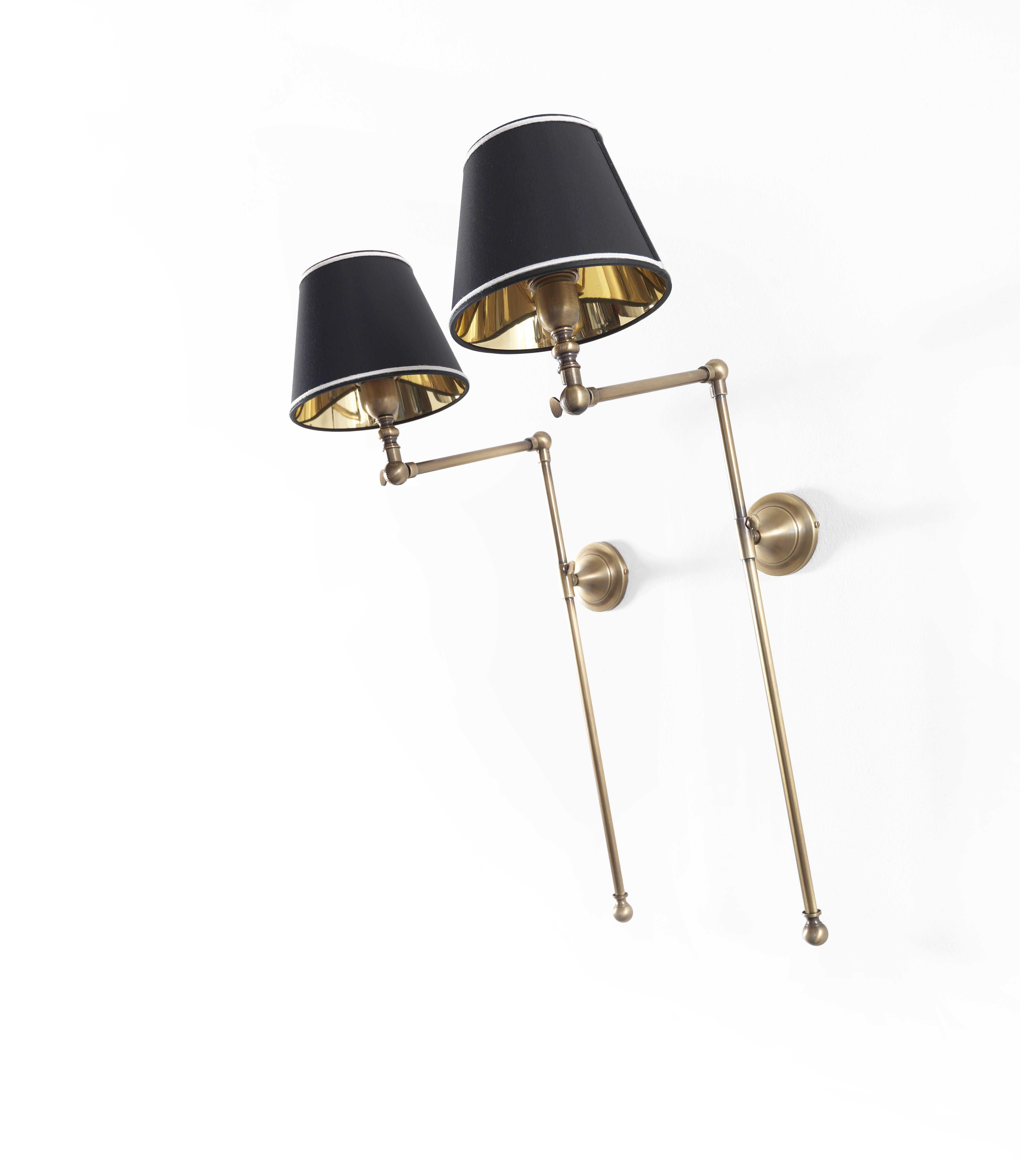 The Amy wall lamp is pictured with structure in brass and iron. gold finishing. Shades with black chinette fabric with white details.   
   