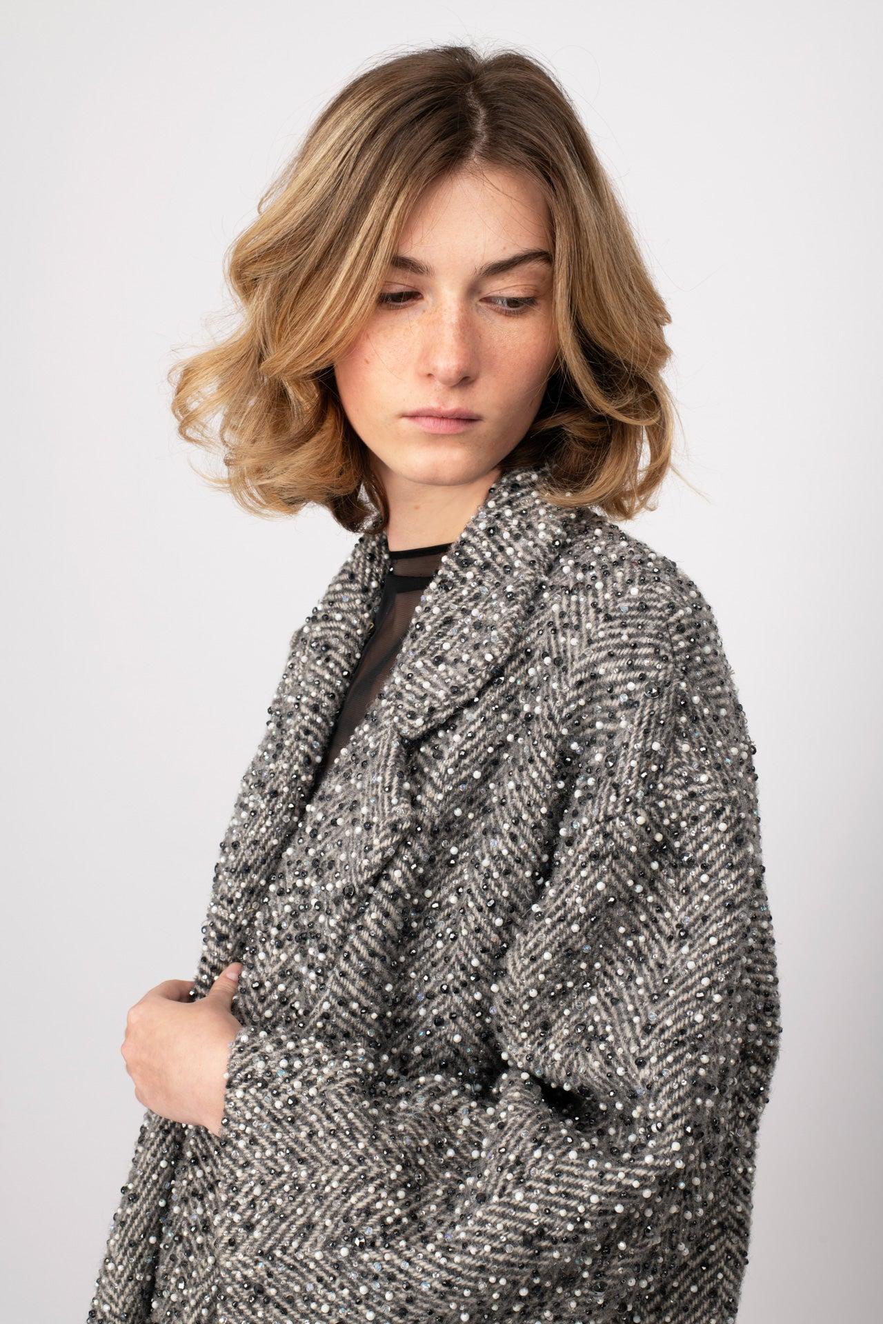 Cappotto scintillante disegnato da Gianfranco Ferré negli anni '80 con ricamo a mano a copertura totale su tessuto di tweed di lana e filati a spina di pesce grigi e neri. Impreziosito da jais e strass grigi, bianchi e antracite, che rendono questo