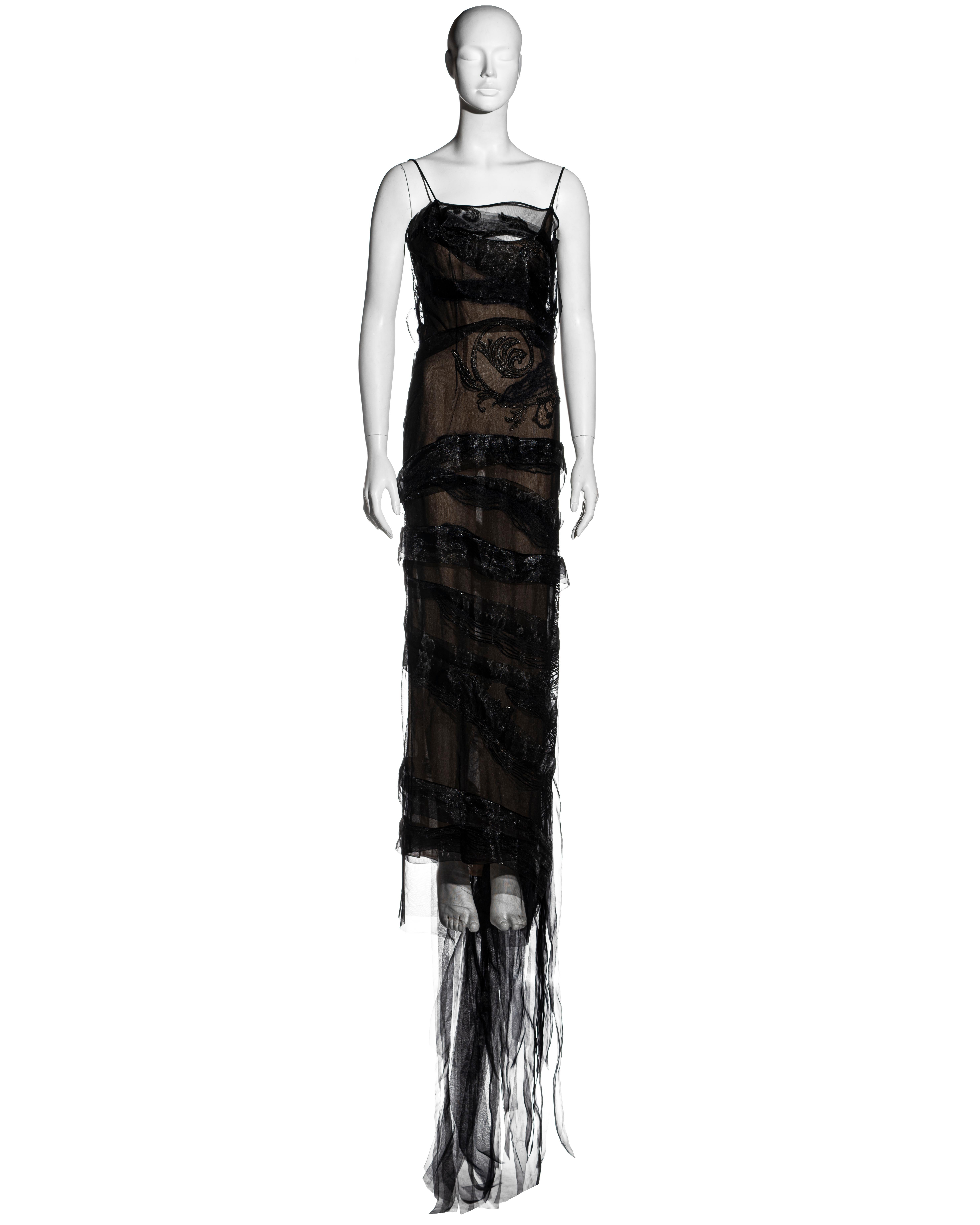 ▪ Gianfranco Ferre black silk organza evening dress
▪ Multiple strips of organza wrap around the dress finishing at the back as a long train 
▪ Spaghetti straps 
▪ Asymmetric neckline 
▪ Embroidered designs on the bodice 
▪ Lace trim at the back
▪