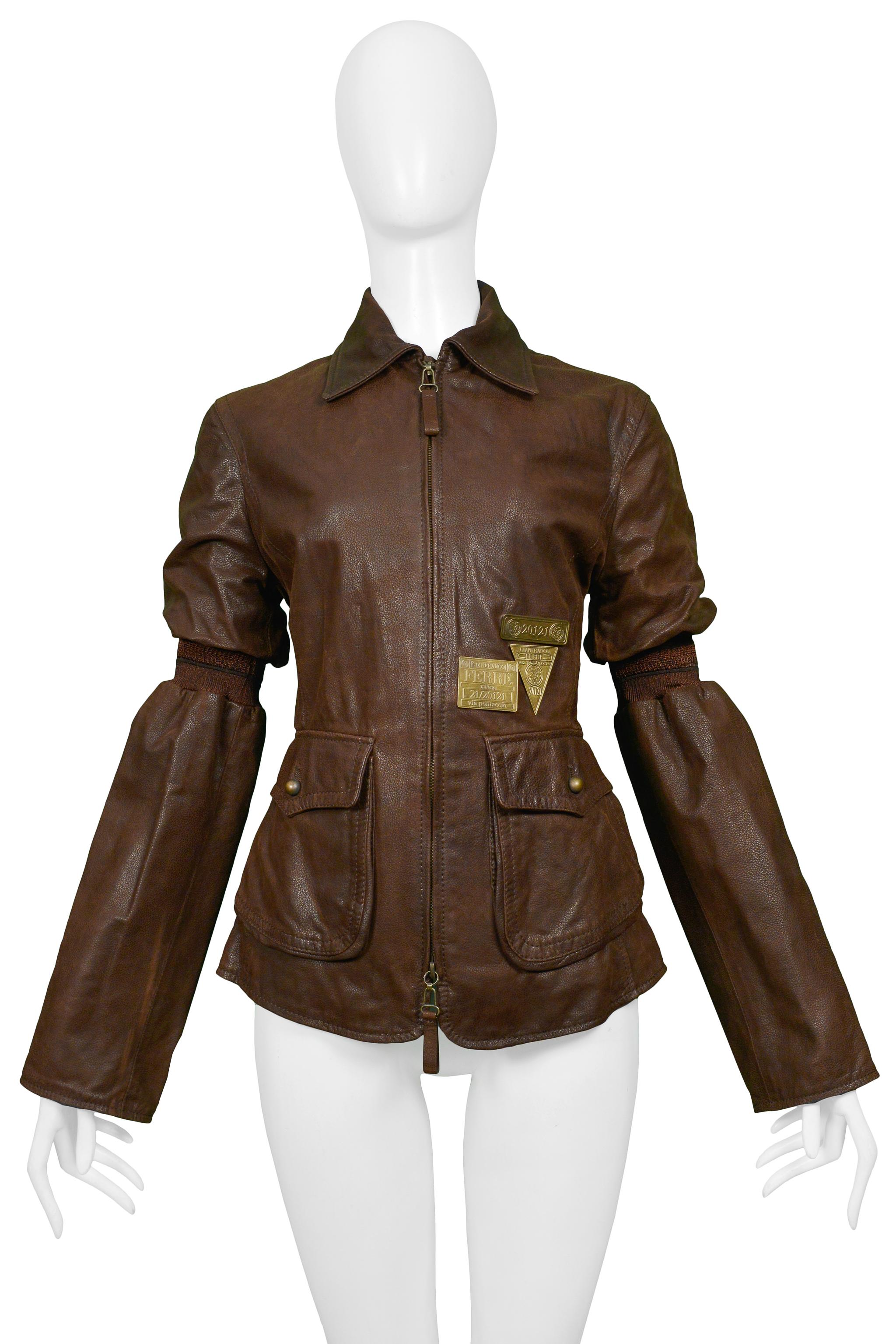 Resurrection is excited to offer a vintage Gianfranco Ferre brown leather aviator jacket featuring two front flap pockets, a two-way center-front zipper with leather pulls, brass hardware, buttons, signature plaques, and striped bands above the