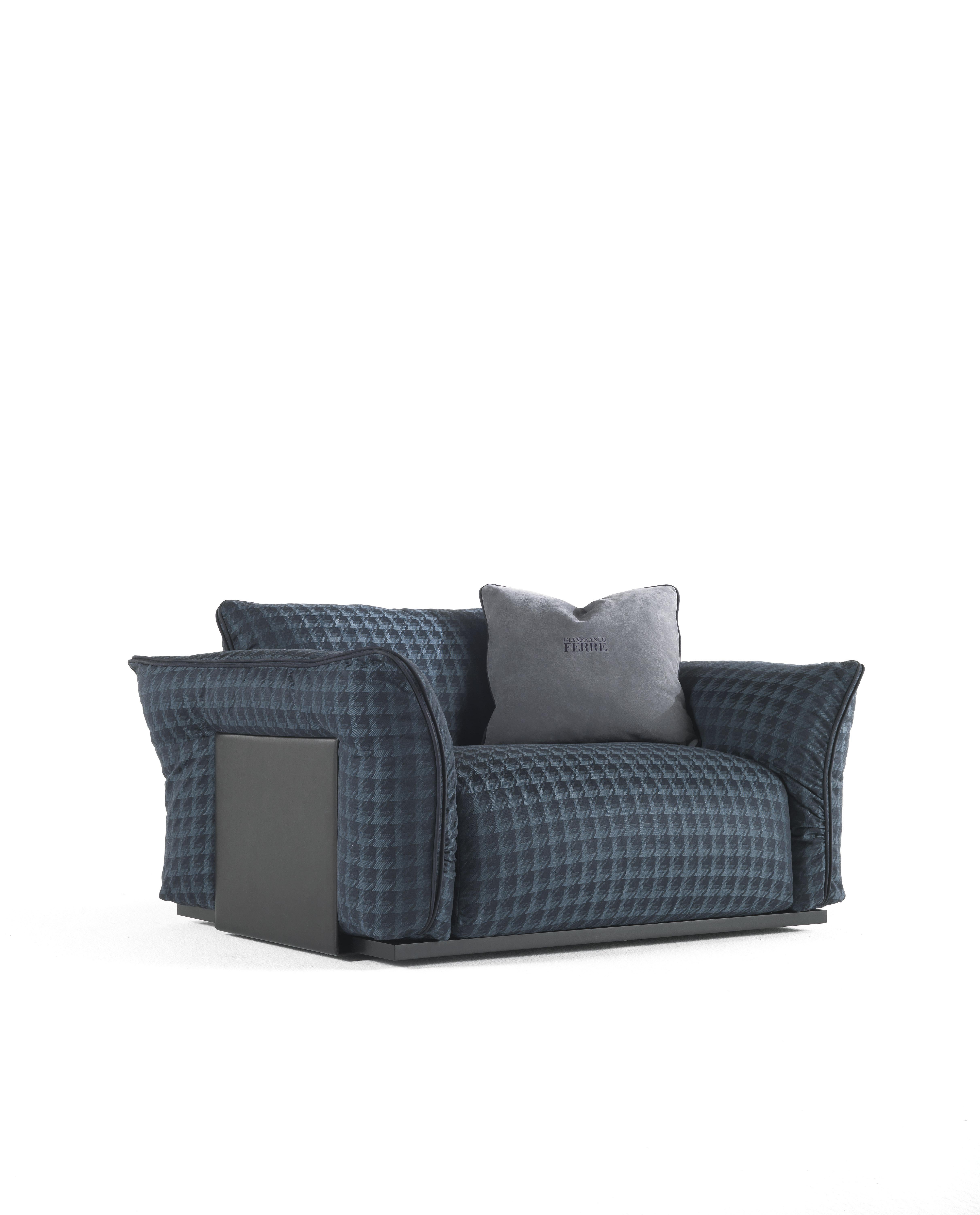 An attractive armchair with a comfortable seat and a contemporary design. The geometric volumes are emphasized by the external plates in metal upholstered leather and by the piping in the same material. The upholstery in fabrics inspired by men's