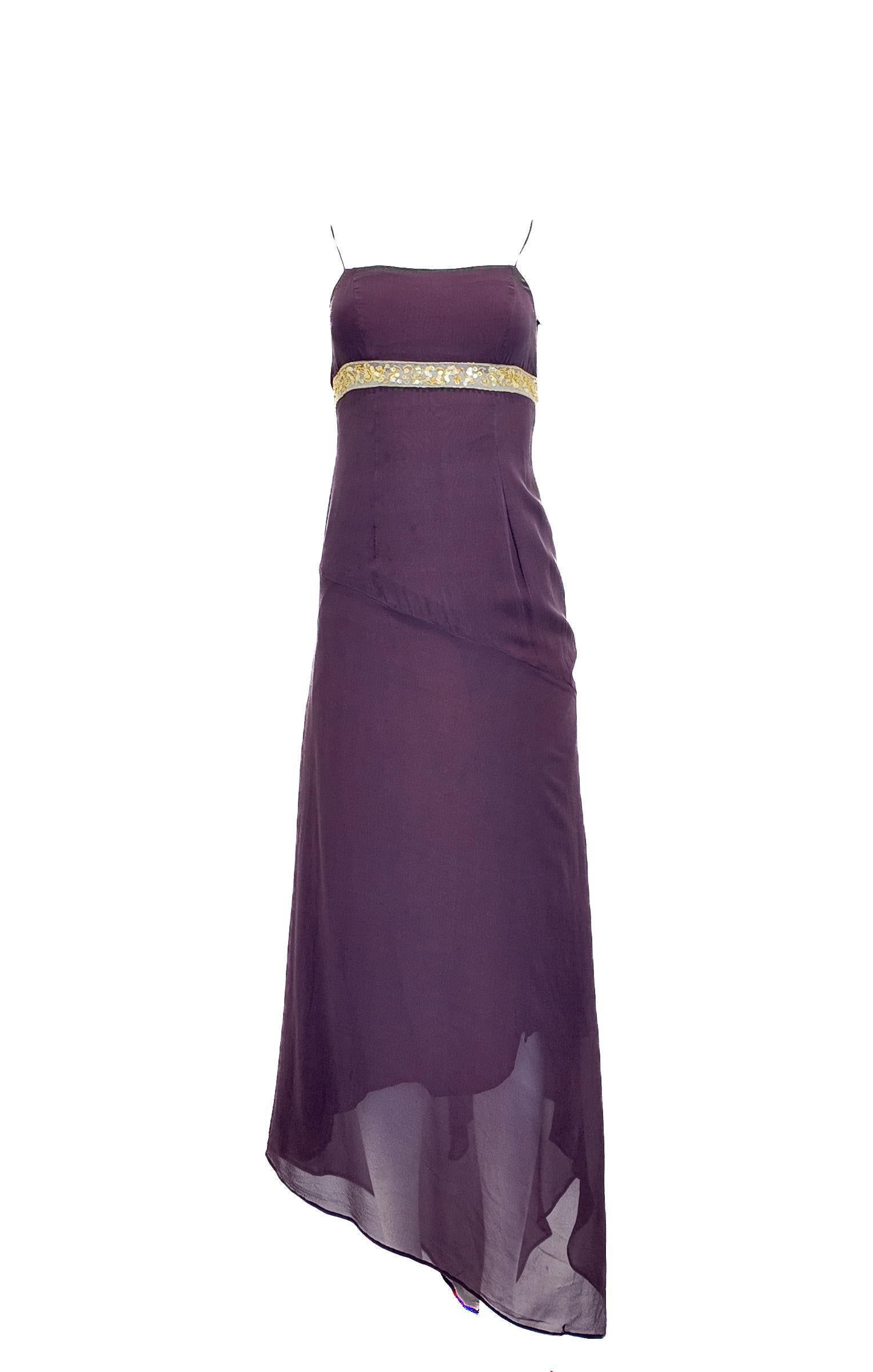 Questo abito di Gianfranco Ferrè in un ricco color porpora melanzana presenta una vita impero di paillettes dorate e un elegante orlo asimmetrico. Realizzato in seta pregiata e completamente foderato, offre comfort e raffinatezza. Ideale per eventi