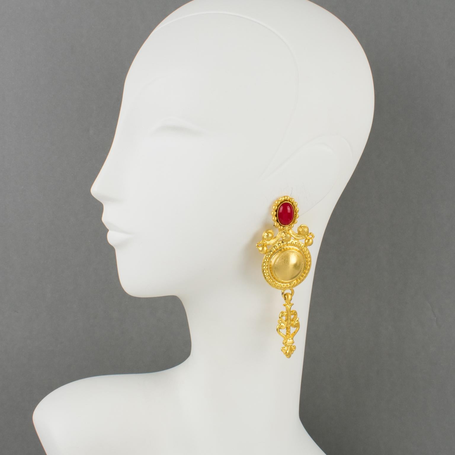 These stunning couture clip-on earrings were designed by Gianfranco Ferre and made in Italy. The statement design features a gilt metal baroque shape, a semi-mat finish aspect with lots of texture, and carving compliment with Gripoix red poured