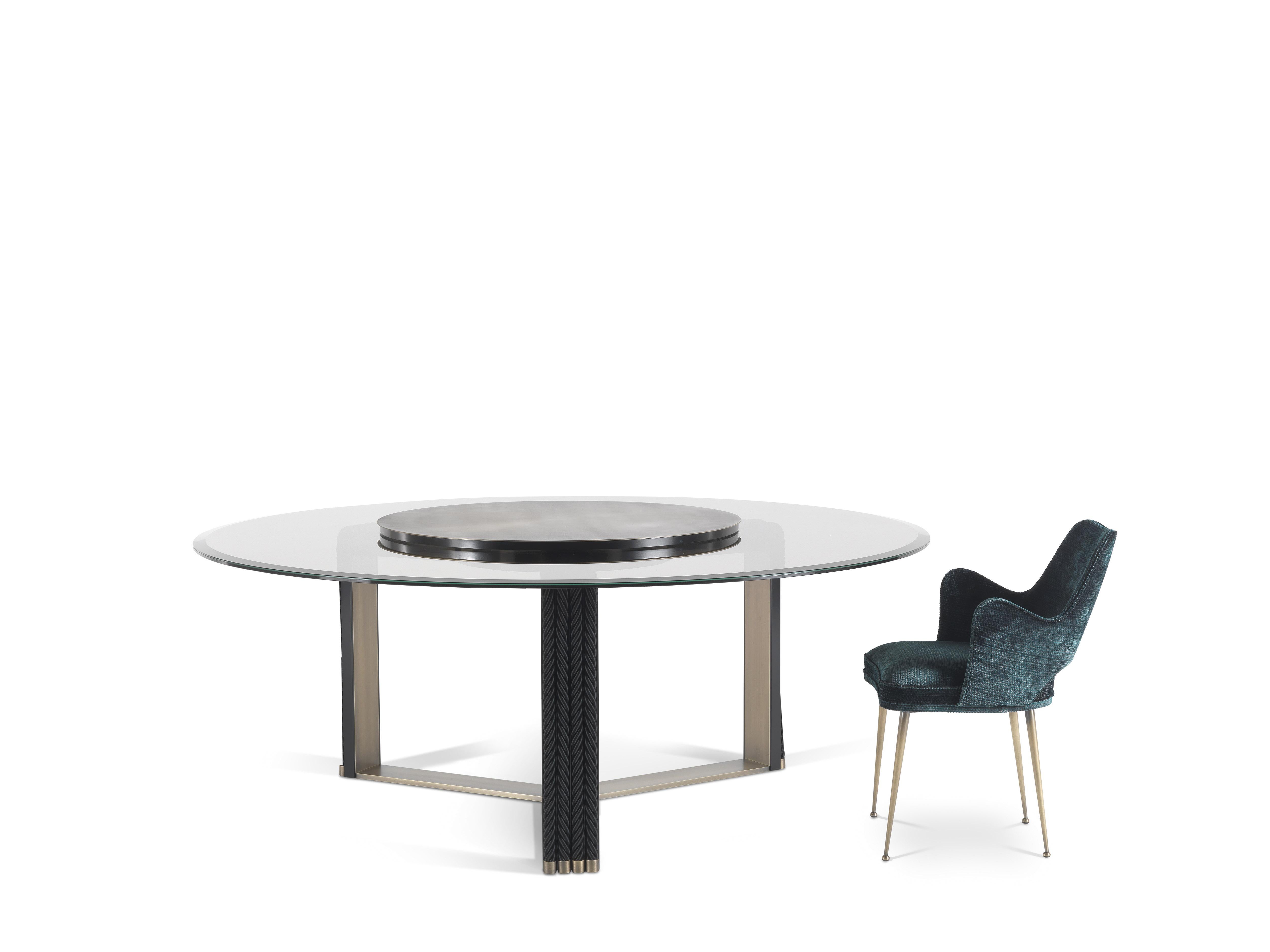 Protagonist of the dining room, the imposing Glasgow table has a coupled and ground bronzed glass top, anchored to a brass disc and equipped with removable Lazy Susan. The unique base in bronzed brass consists of a single piece structured on three