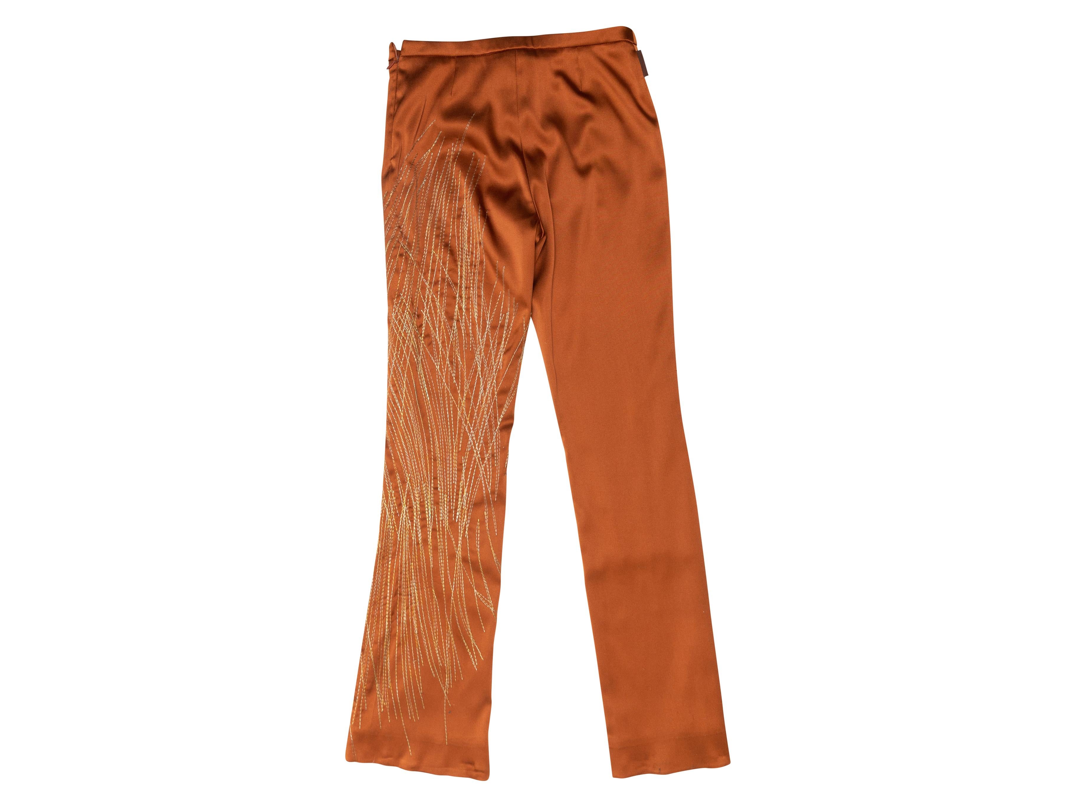 Product details: Vintage orange satin pants by Gianfranco Ferre Jeans. Abstract metallic gold embroidery at leg. Concealed zip closure at side. Designer size 38. 28