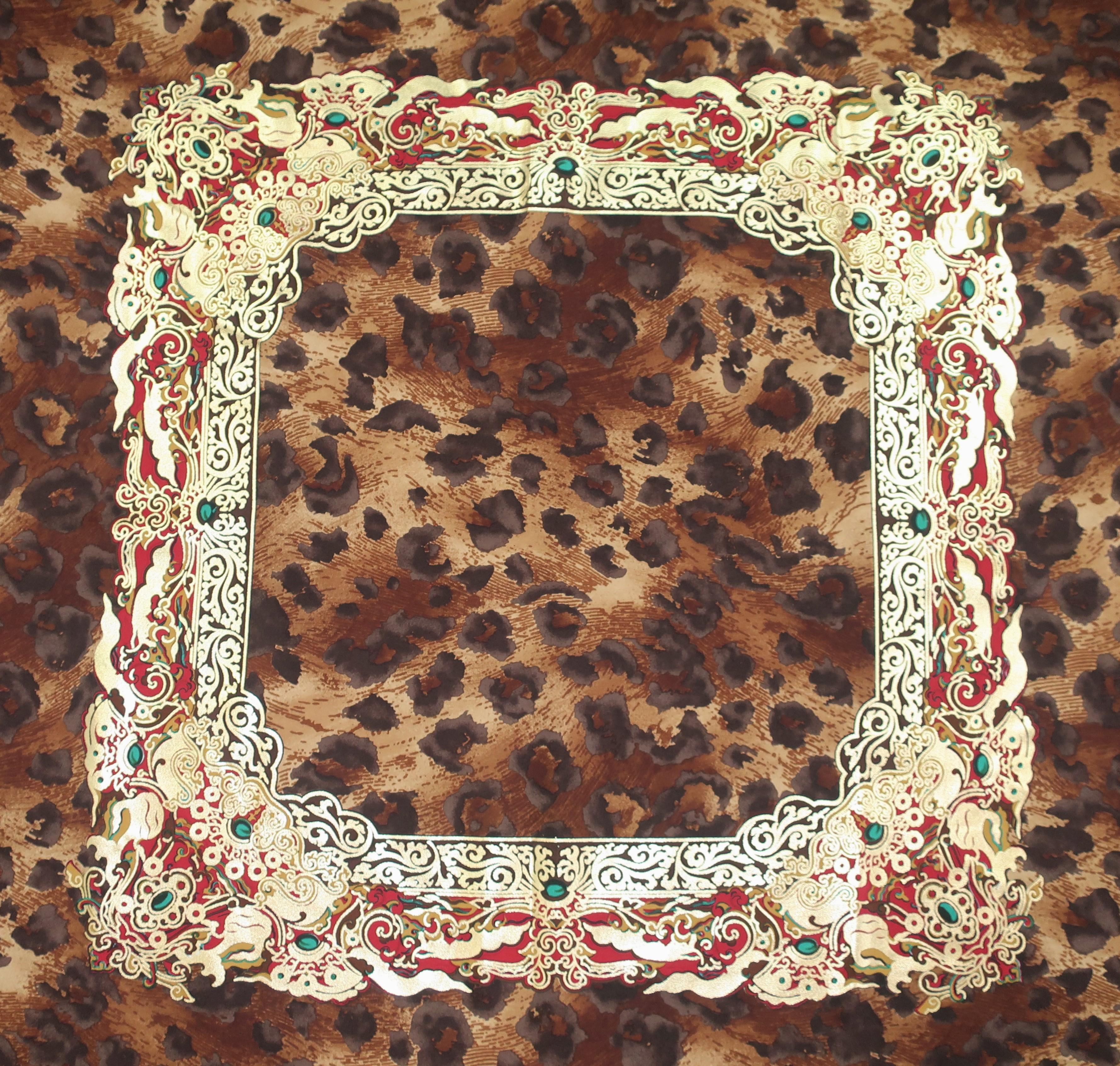 This Gianfranco Ferre silk scarf is impressive in more ways than one.  The large scale is the perfect backdrop for a brown leopard print with an eye catching gold framed accent at the center embellished with touches of emerald green and red.  The