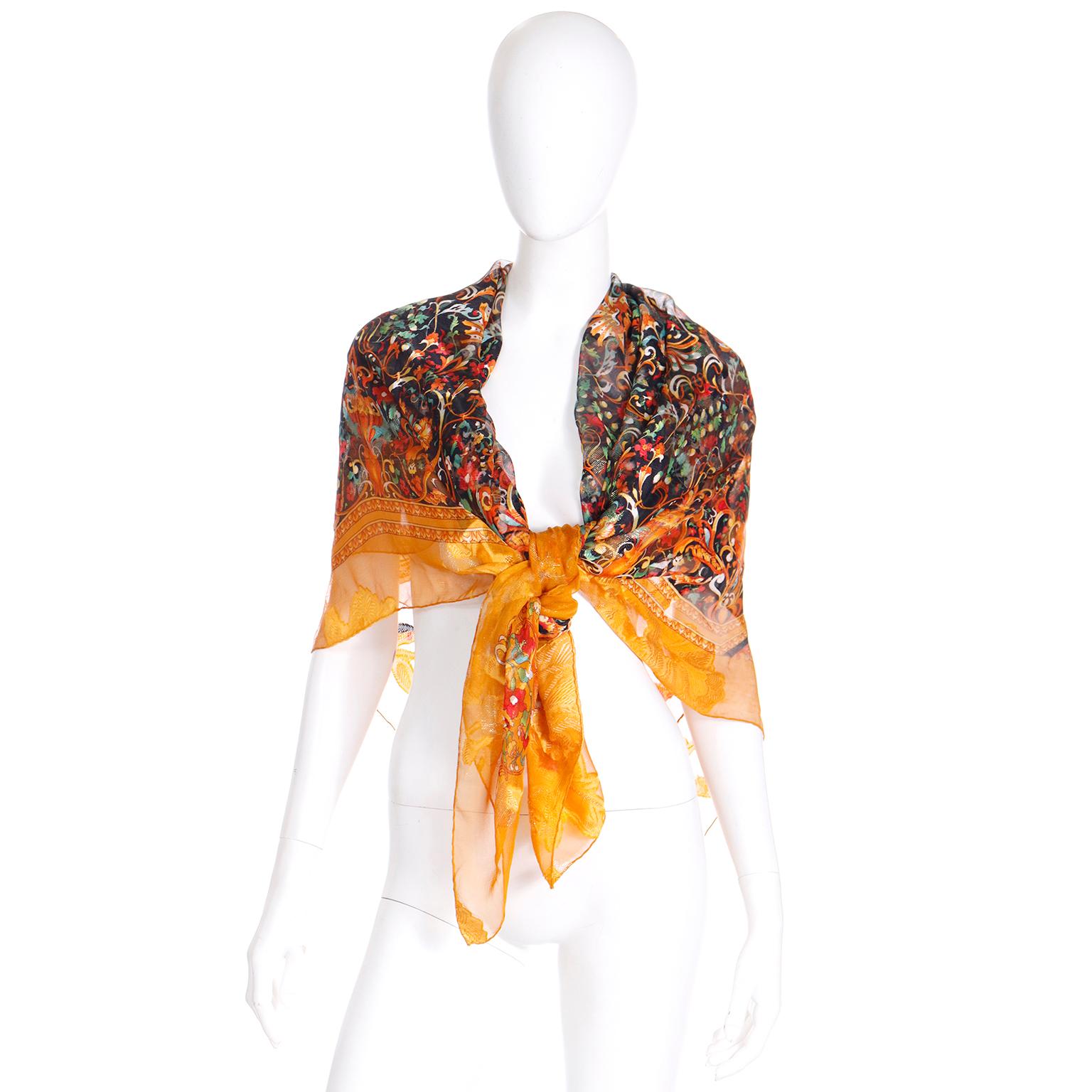 This is an elegant vintage silk scarf from Gianfranco Ferre. The beautiful luxe print is in rich shades of tangerine orange green, red, yellow, white, and black. The ultra fine gold lame yarns add a luxurious shimmer to the scarf and we love the
