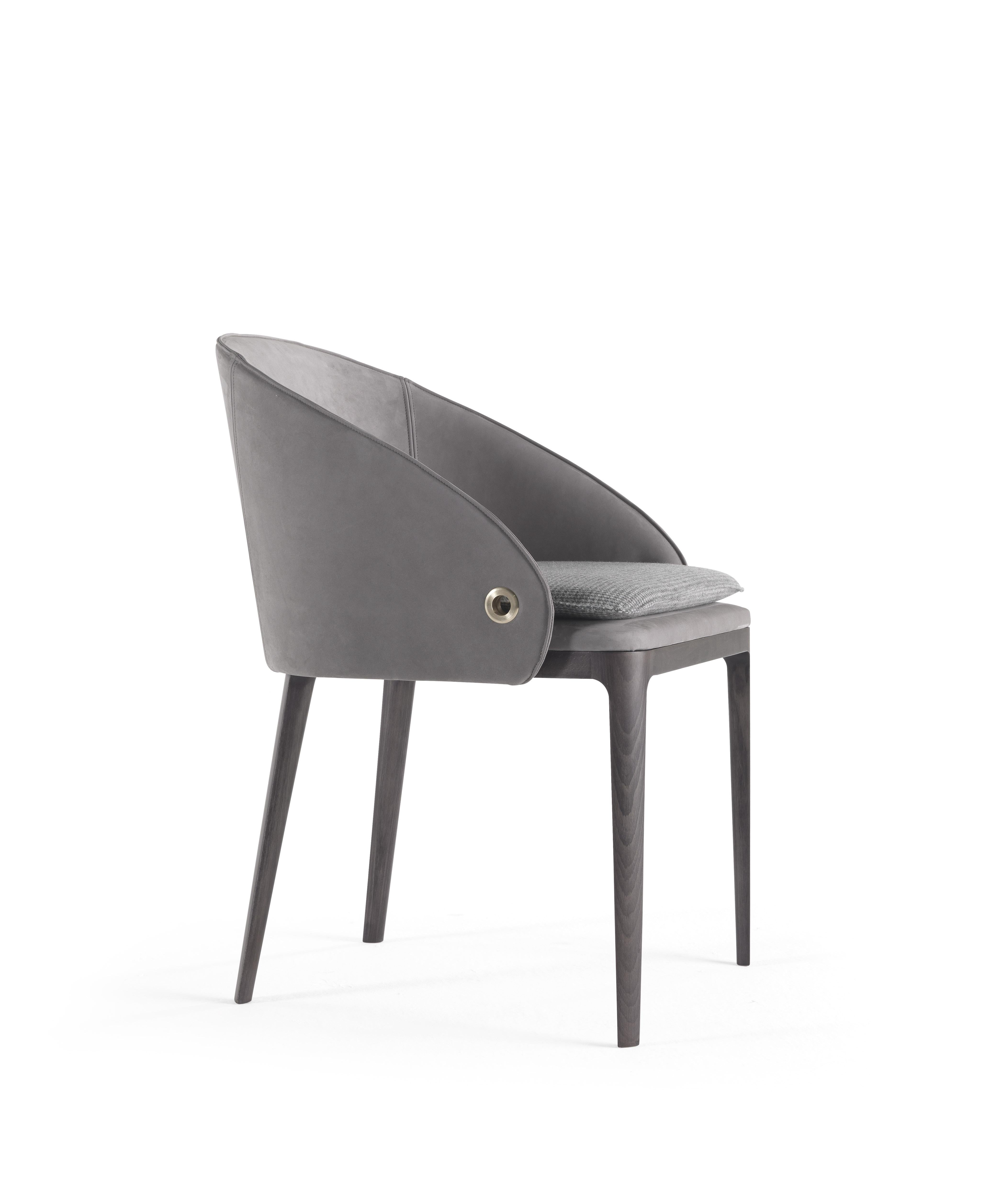 Una silhouette elegante e linee pulite per la nuova sedia Rio. Il contrasto tra la struttura sottile delle gambe in finitura grigio fumo e la forma avvolgente della seduta rivestita con i tessuti della collezione rende la sedia originale e