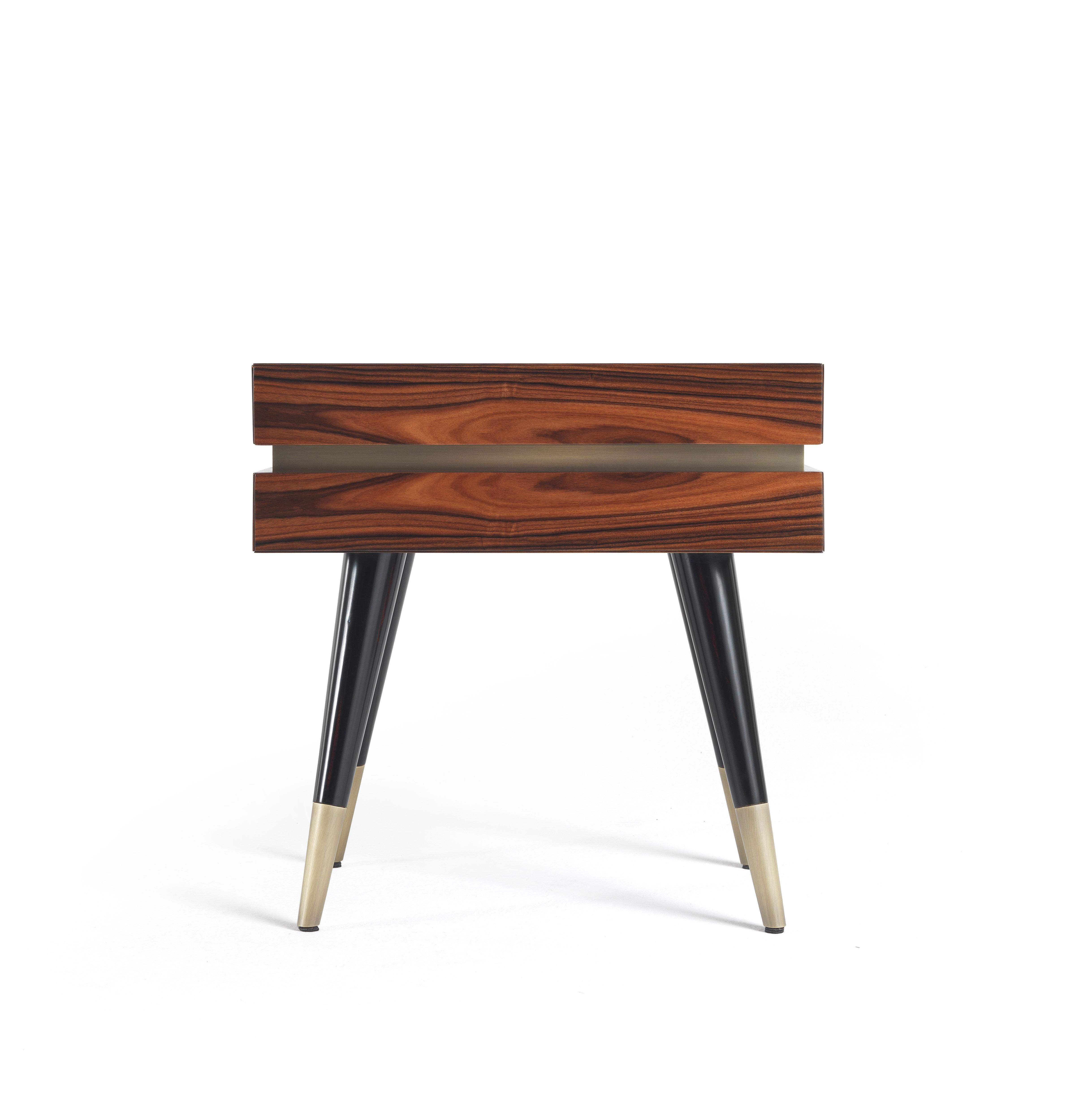 Assembled at 45°, with a rosewood sheet that rotates around the entire cabinet giving a sense of continuity, the Sean night table features the presence of sloping legs with brass tips and handleless drawers with bronzed brass band. A combination of