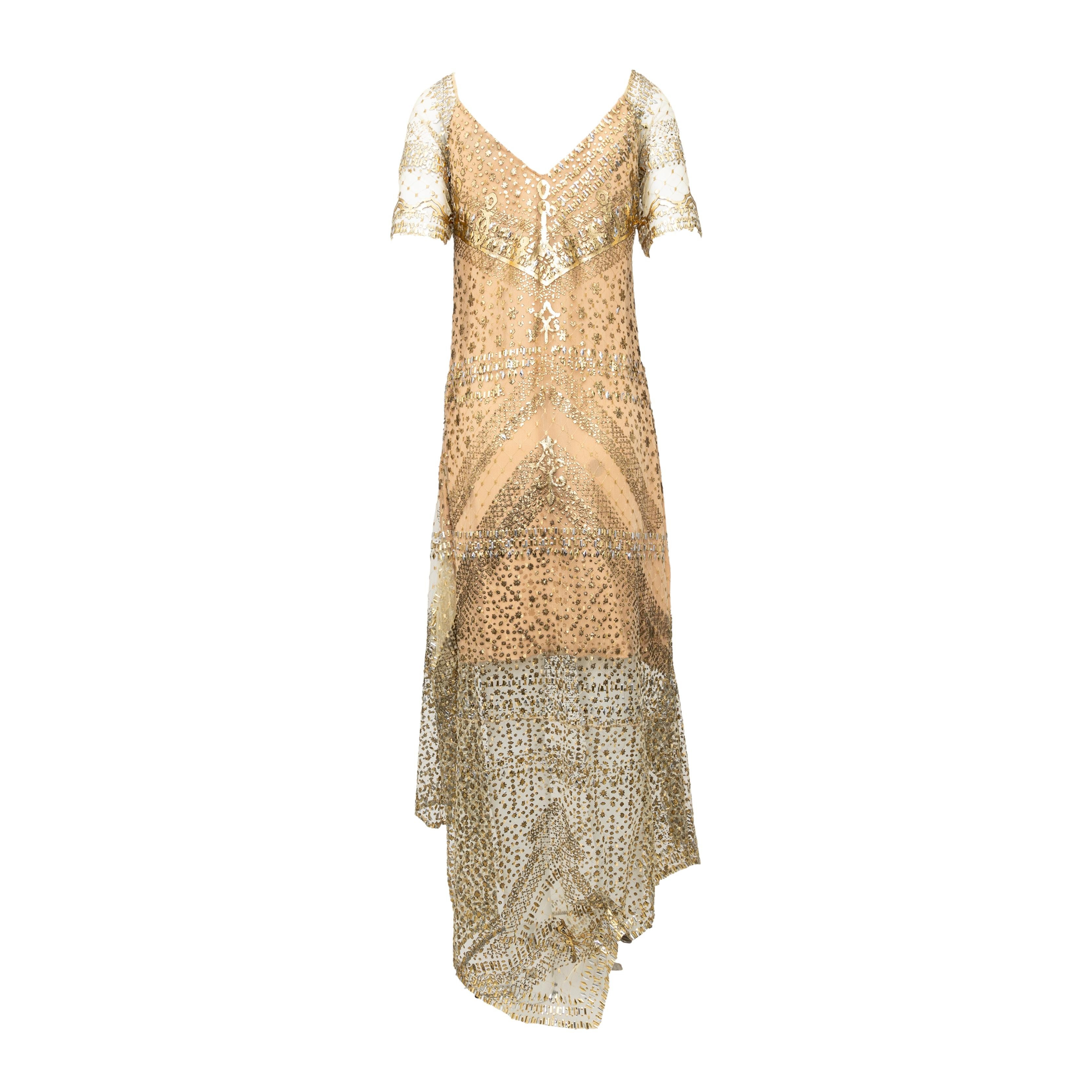 Crafted by Gianfranco Ferré, this glamorous 80s dress boasts stunning golden and silver embellishments and studs on a mesh fabric. Lined for full coverage, the maxi length and V-neck with short sleeves create an elegant silhouette. The asymmetric