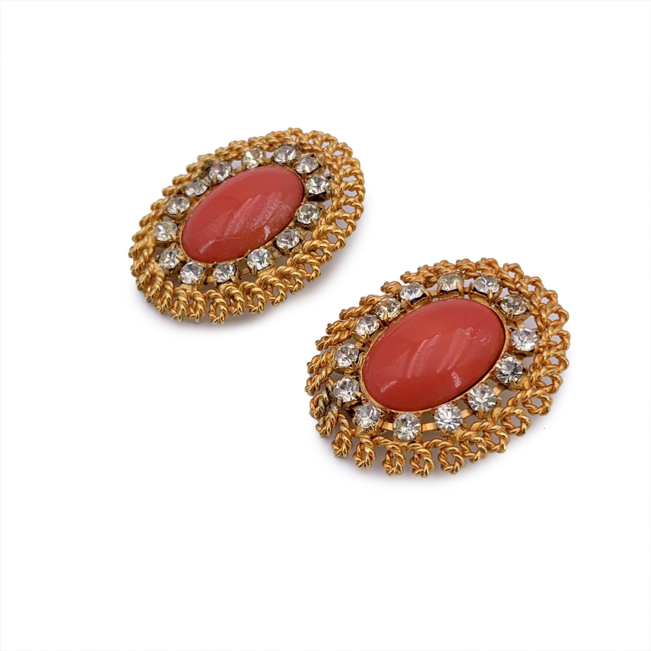Step into the glamour of the 80s with these gorgeous vintage Gianfranco Ferré oval earrings. A true statement piece, these earrings feature a striking gold metal structure that elegantly frames a central resin coral-colored cabochon. Surrounding the