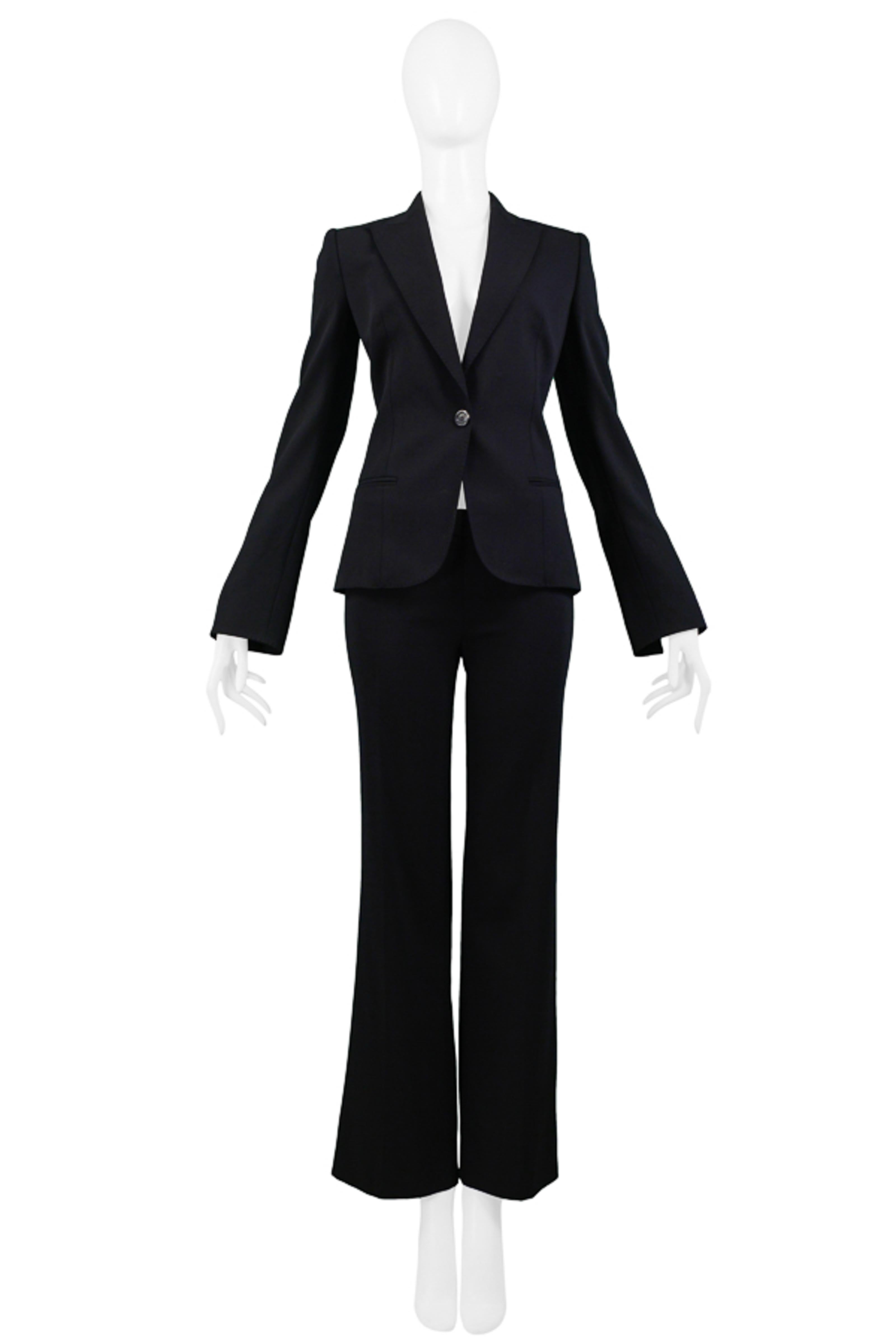 Resurrection Vintage is excited to offer a vintage Gianfranco Ferre classic black wool suit featuring a fitted one-button blazer, notch collar, sharp lapel, slit pockets, and slits at the cuff with exposed logo trim tape. The matching boot cut pants