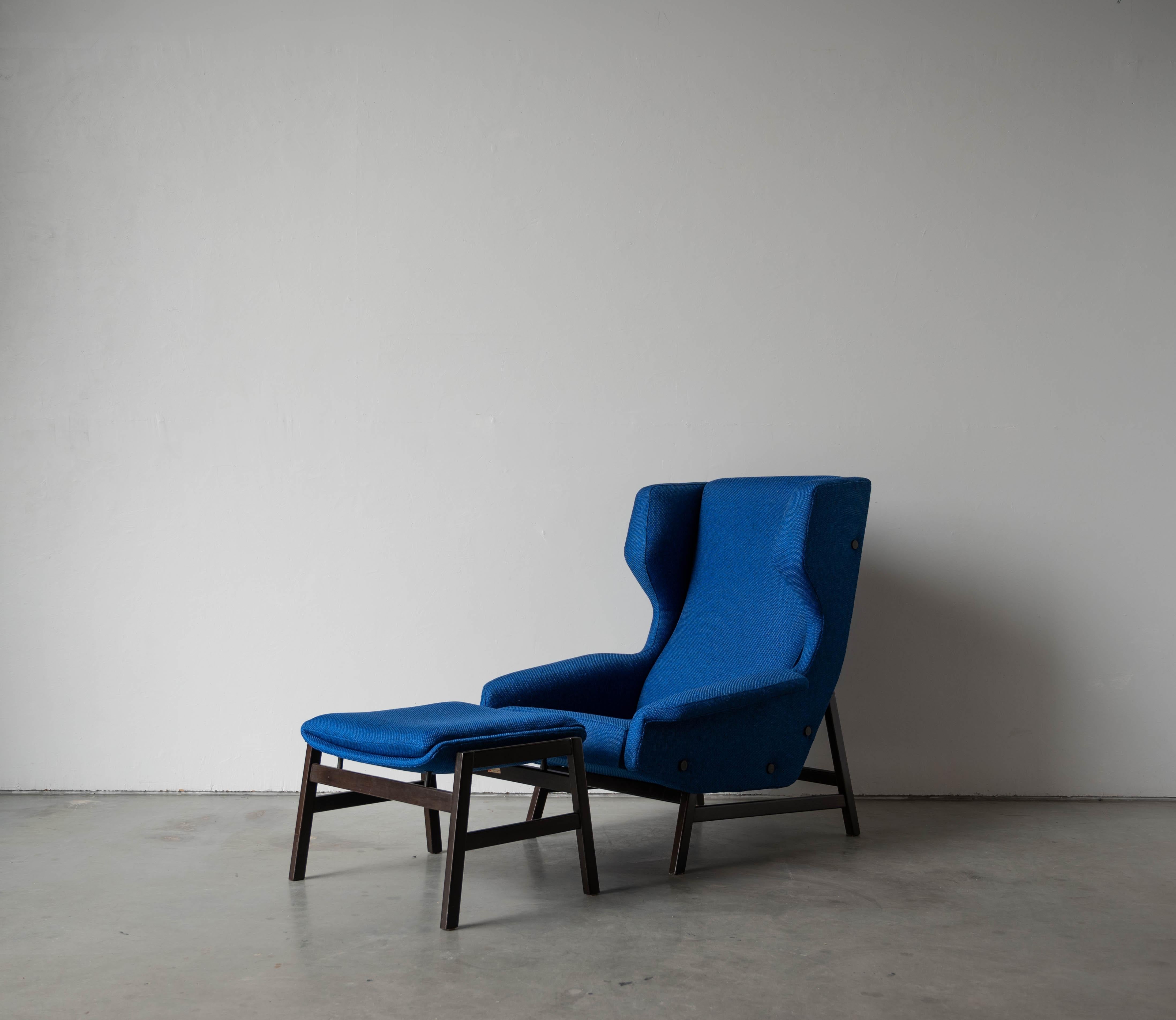 A lounge chair with ottoman designed by Gianfranco Frattini and produced by Cassina, Italy c. 1959. Executed in dark-stained walnut, blue fabric, with makers metal plaque. 

Stated dimensions are of lounge chair. Ottoman measures H 42 cm / 16.5