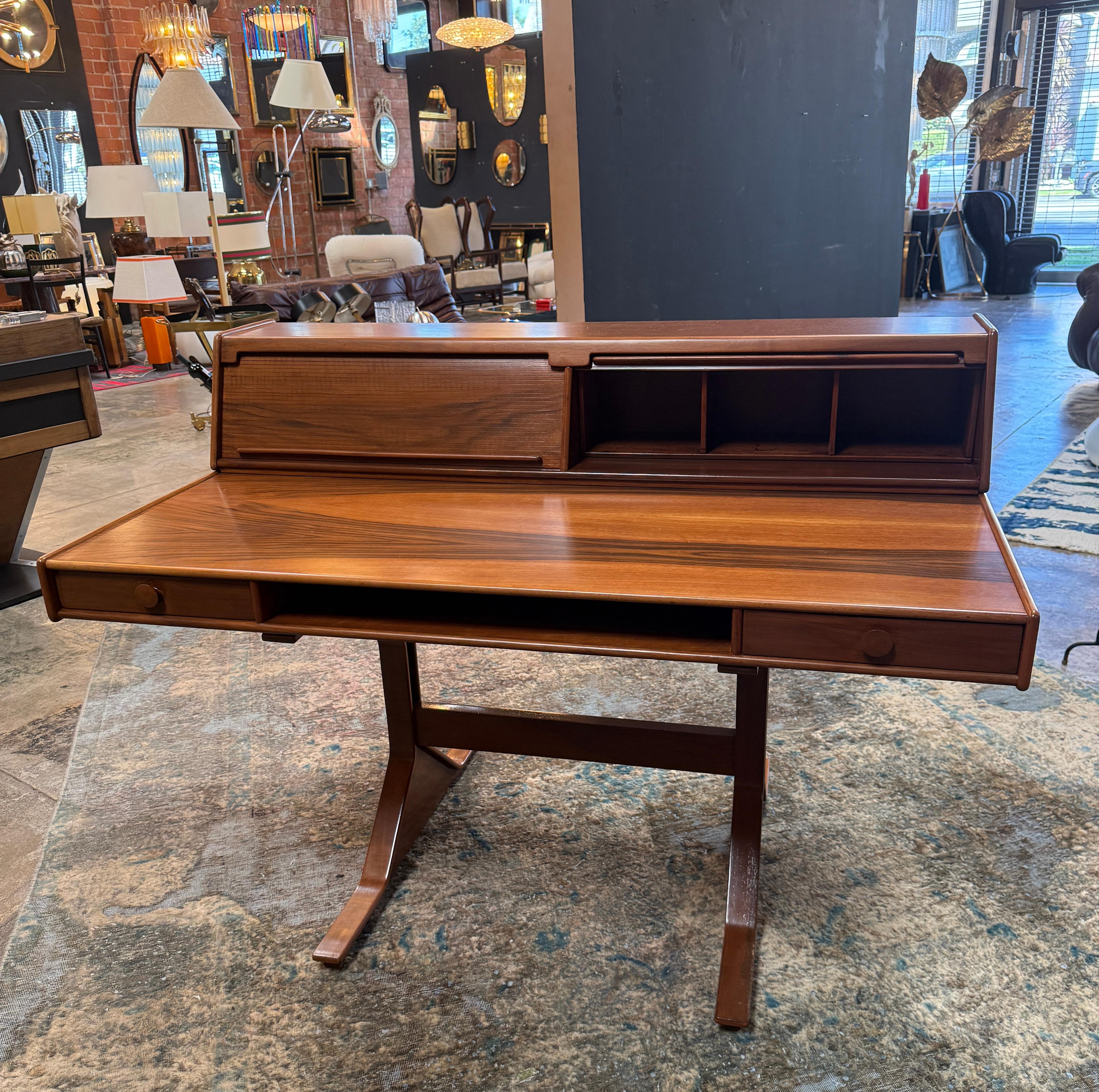 Designed by Gianfranco Frattini in the 1960s, this Italian writing desk exemplifies his refined modernist vision. Crafted in walnut with a beautifully figured grain, the desk features a raised back section with a sliding tambour door and open