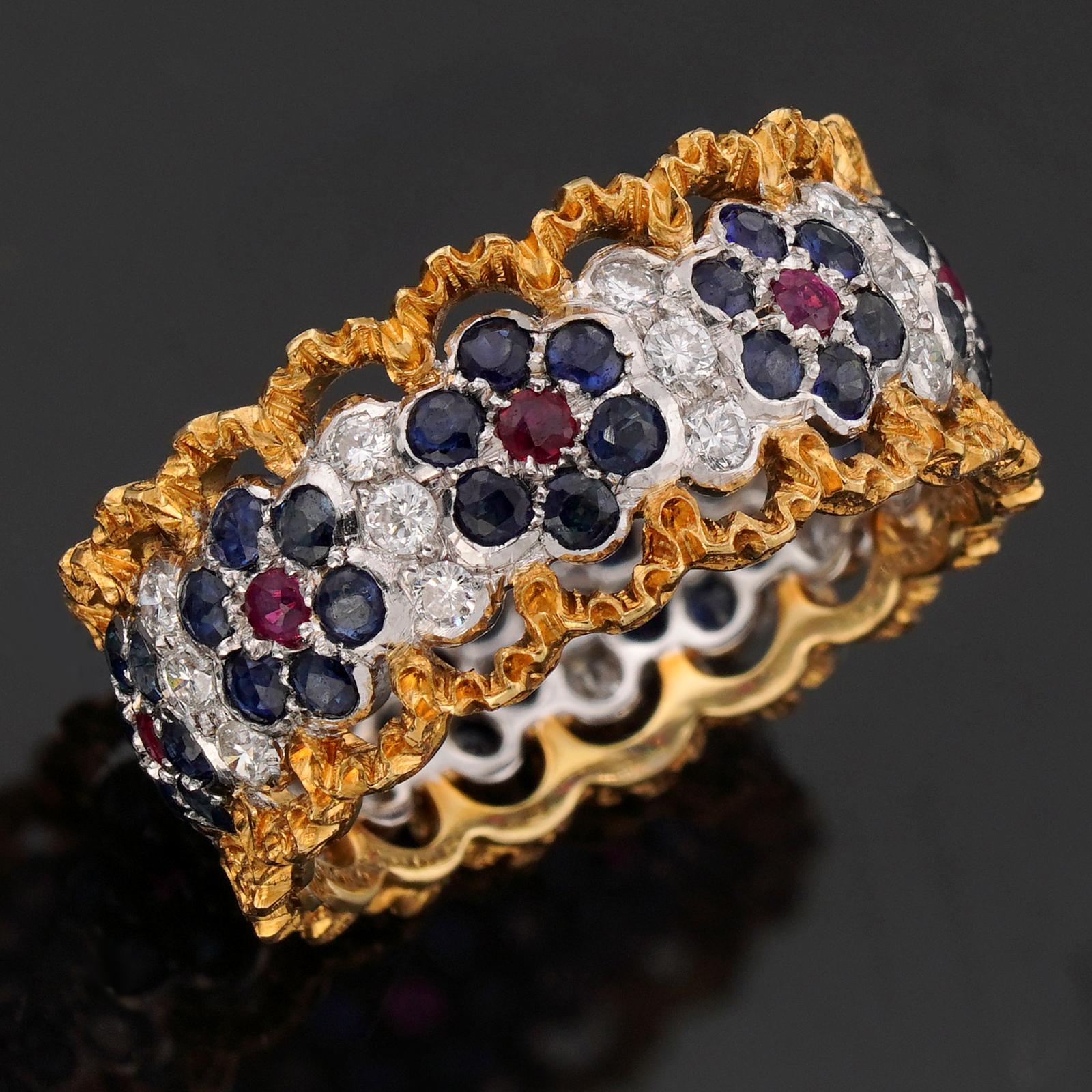 Questo splendido anello di Gianmaria Buccellati presenta un intricato design a fascia realizzato in oro giallo 18 carati e incastonato con diamanti rotondi a taglio brillante, rubini rossi e zaffiri blu. Realizzato in Italia intorno agli anni '1990.