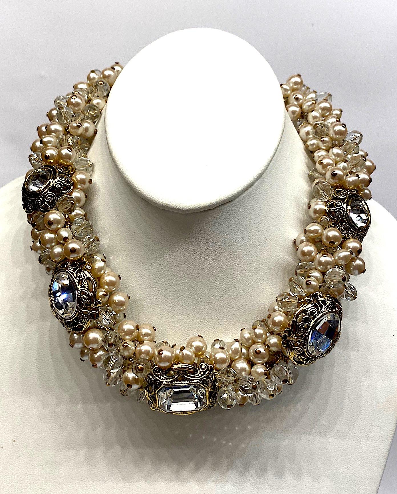 A dramatic necklace by Italian fashion jewelry company De Liguoro circa 1980. Champagne color faux pearls with large and small faceted crystal beads are individually attached to two gold tone chains in a cluster formation. Additionally, within the