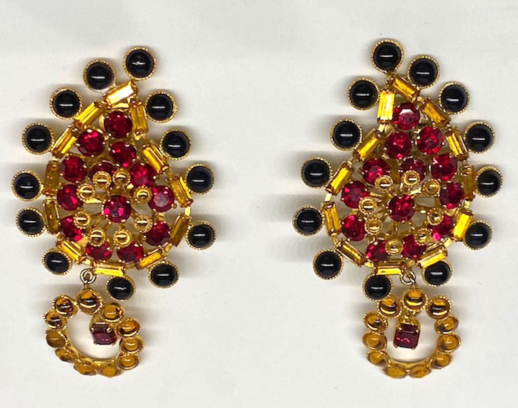 A chick pair of 1980s large cabochon and rhinestone earrings by Di Liguoro of Italy. The large black and smaller gold cabochons are glass as are the gold baguette and round red rhinestones. All beautifully set into a shiny gold tone setting. The top