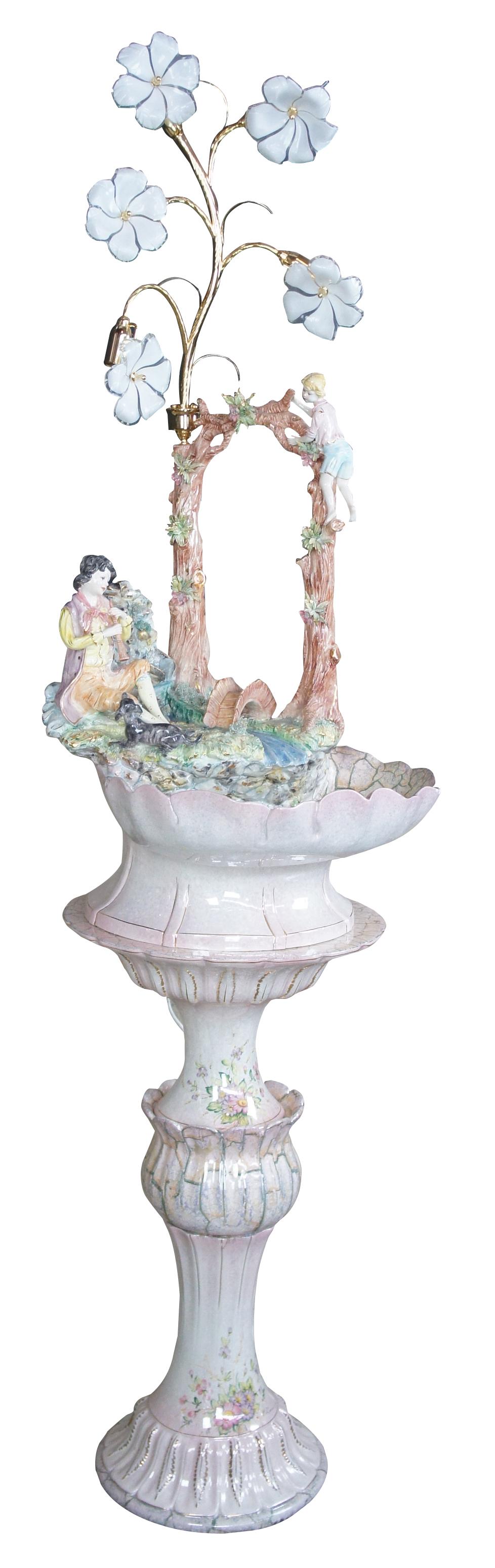 Gianni Lorenzon Italian illuminated fountain with flower petal lamp and hand painted accents. Features a colonial scene with a couple with alongside a waterfall. The gentleman can be seen playing a flute while the lady climbs the nearby tree. The