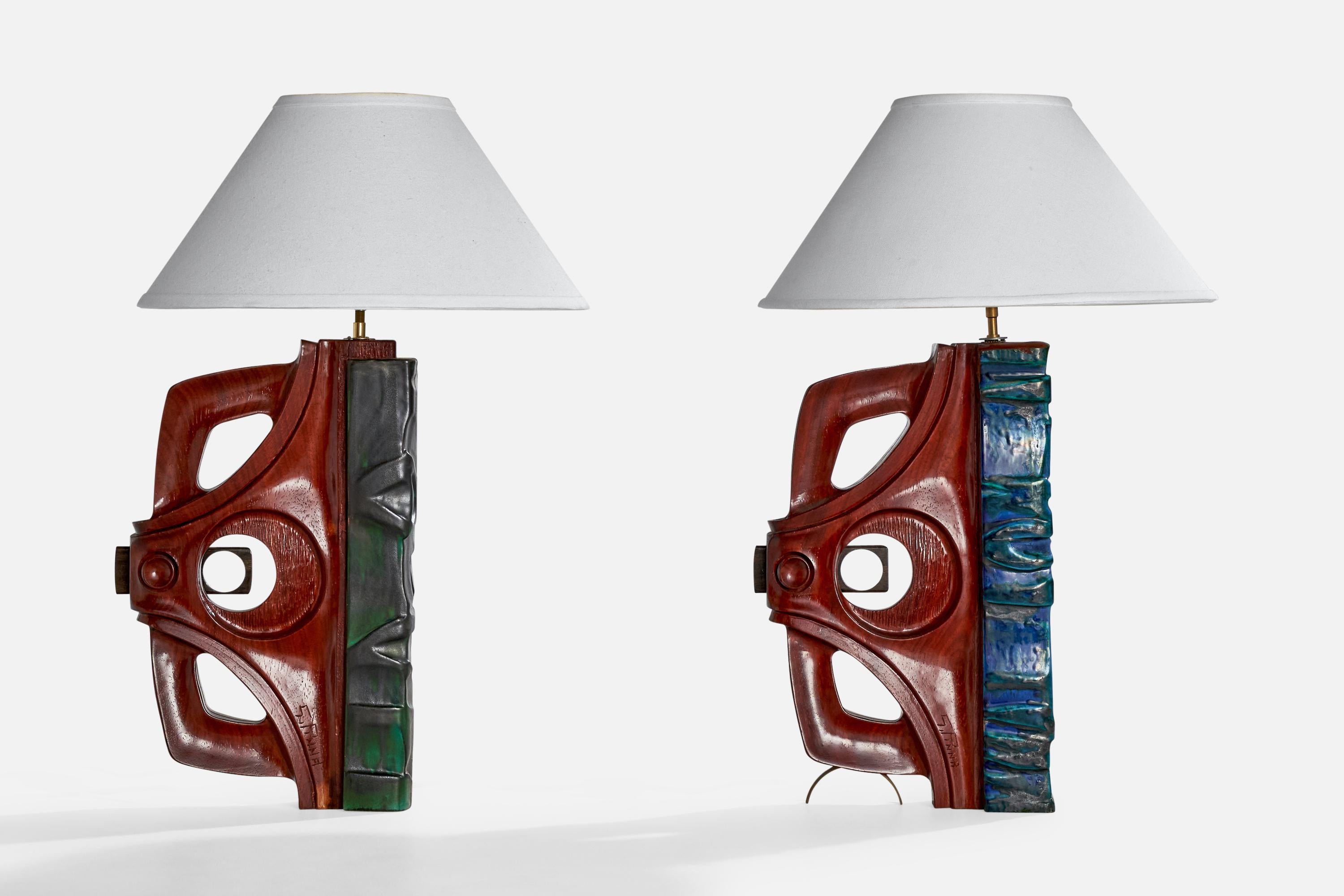 A pair of stained wood and blue green glazed ceramic table lamps designed and produced by Gianni Pinna, Italy, c. 1970s.

Dimensions of Lamp (inches):  20.75“ H x  11“ W x  3.5” D

Dimensions of Shade (inches):  6“ Top Diameter x  16.375“ Bottom