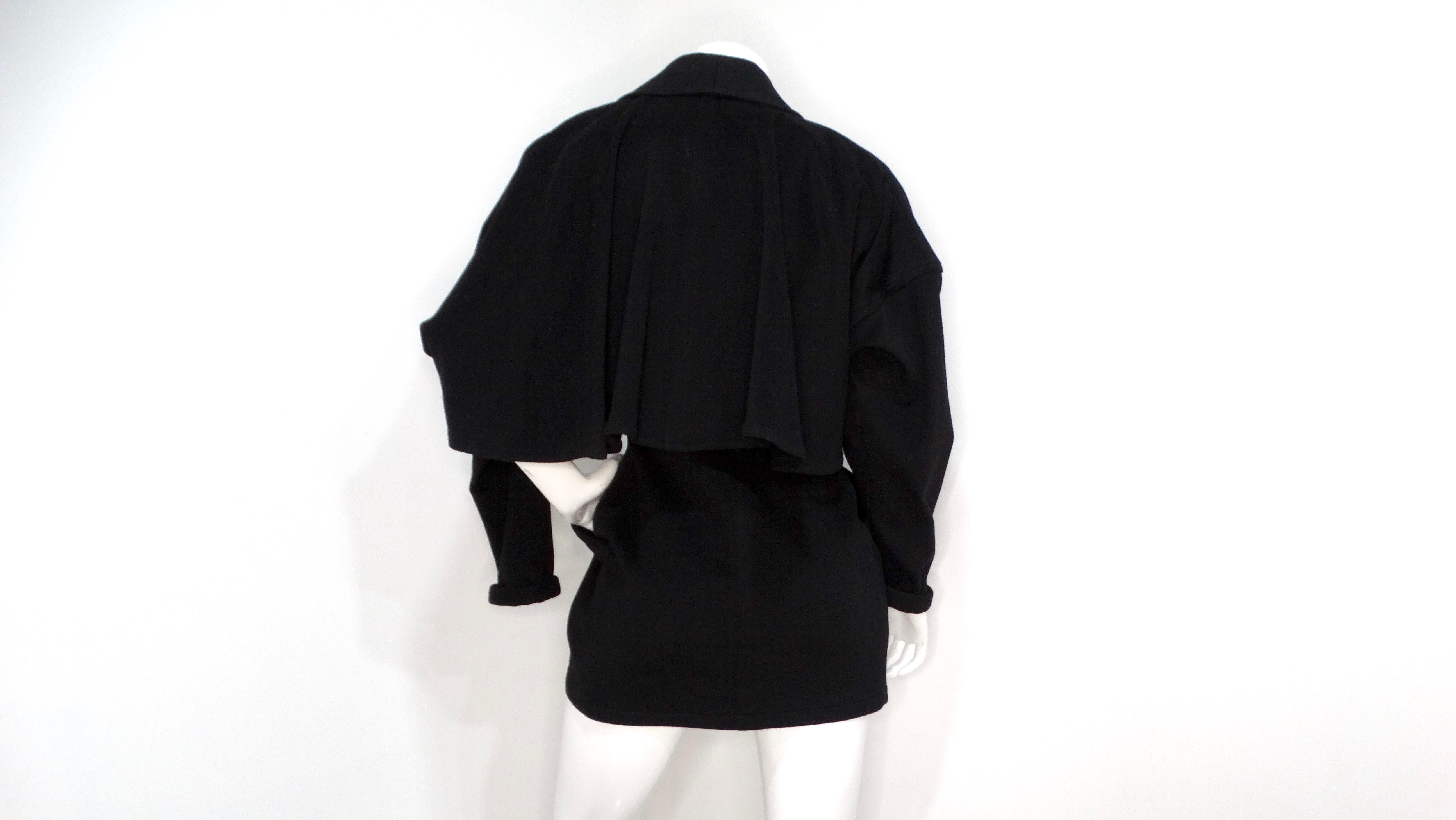 Ti presentiamo l'accattivante giacca Gianni Versace anni '80 in lana nera con dettaglio a mantello. Questo design raffinato è caratterizzato da un'elegante silhouette completamente nera, impreziosita da due vistosi bottoni argentati che stringono la