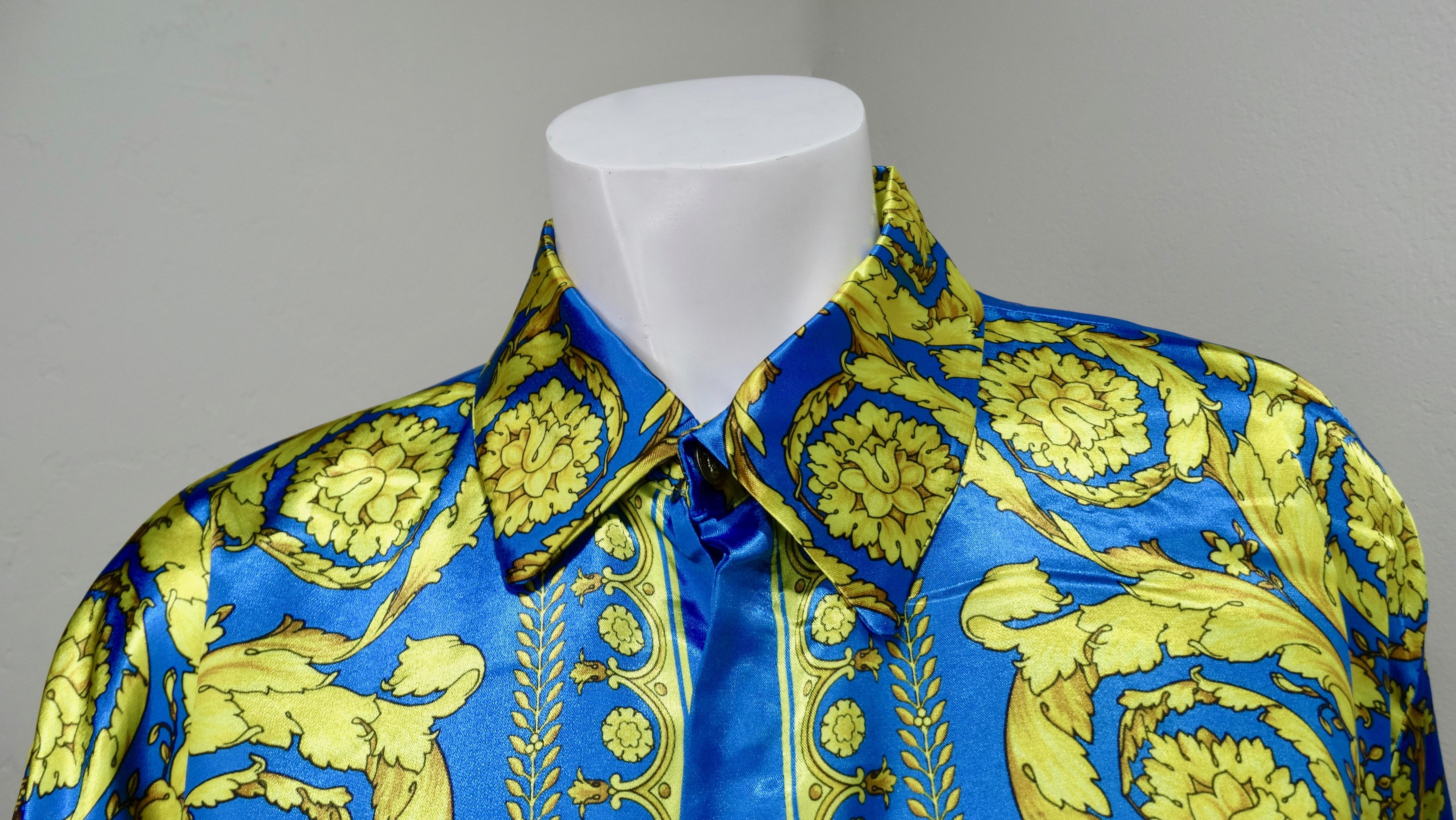 Snag yourself a piece from the Versace archives! Circa 1990s, this shiny electric blue and gold Silk button down shirt features one of Versace's signature Baroque designs mixed with floral arrangements and crowns. Includes a hidden button closure