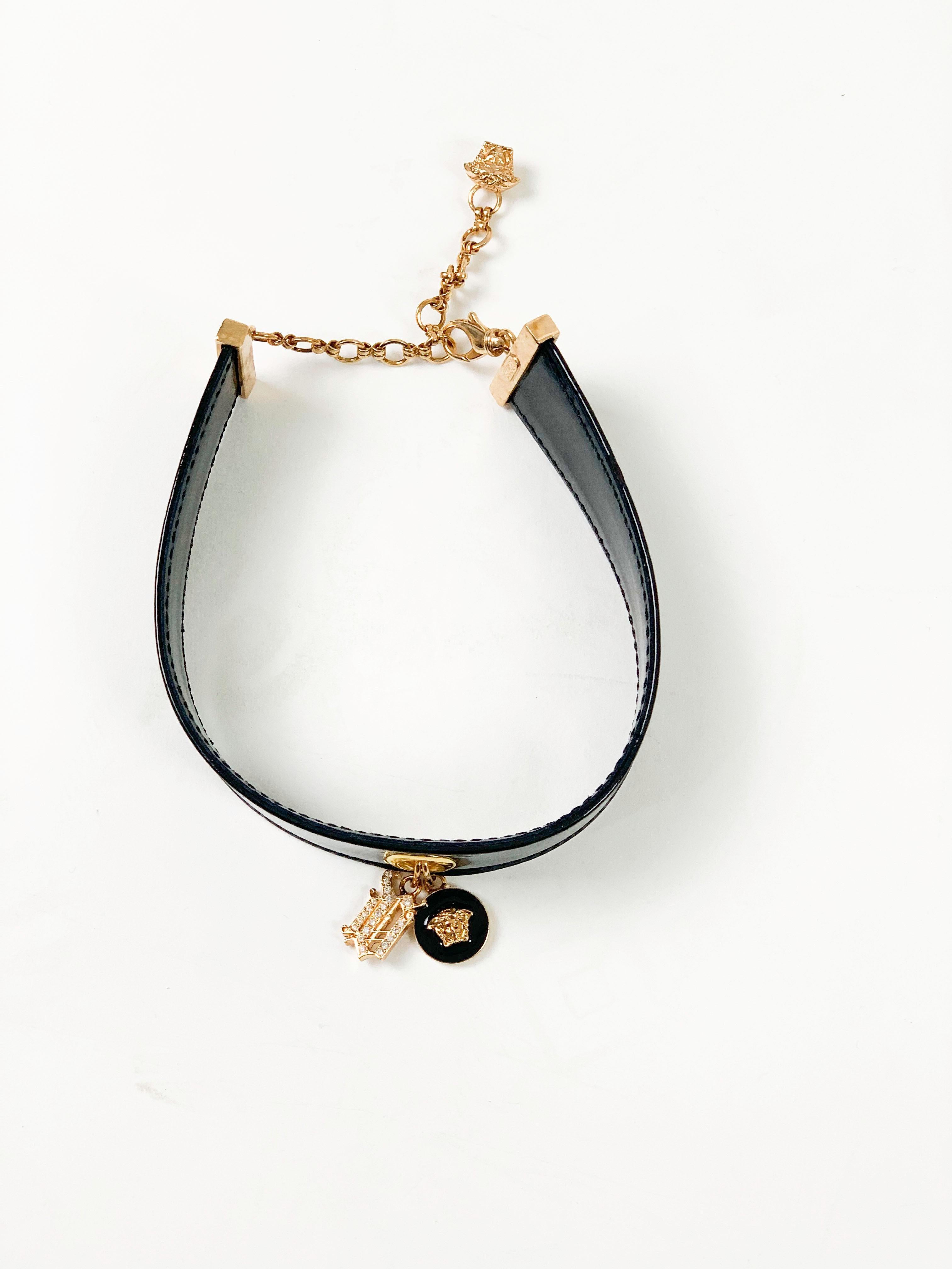Famous for his edgy and breaking the boundaries style, Gianni Versace always created items to turn heads. This patent leather choker is just that. Made in Italy the choker features a wide patent leather strap with two gold tone pendants. One the