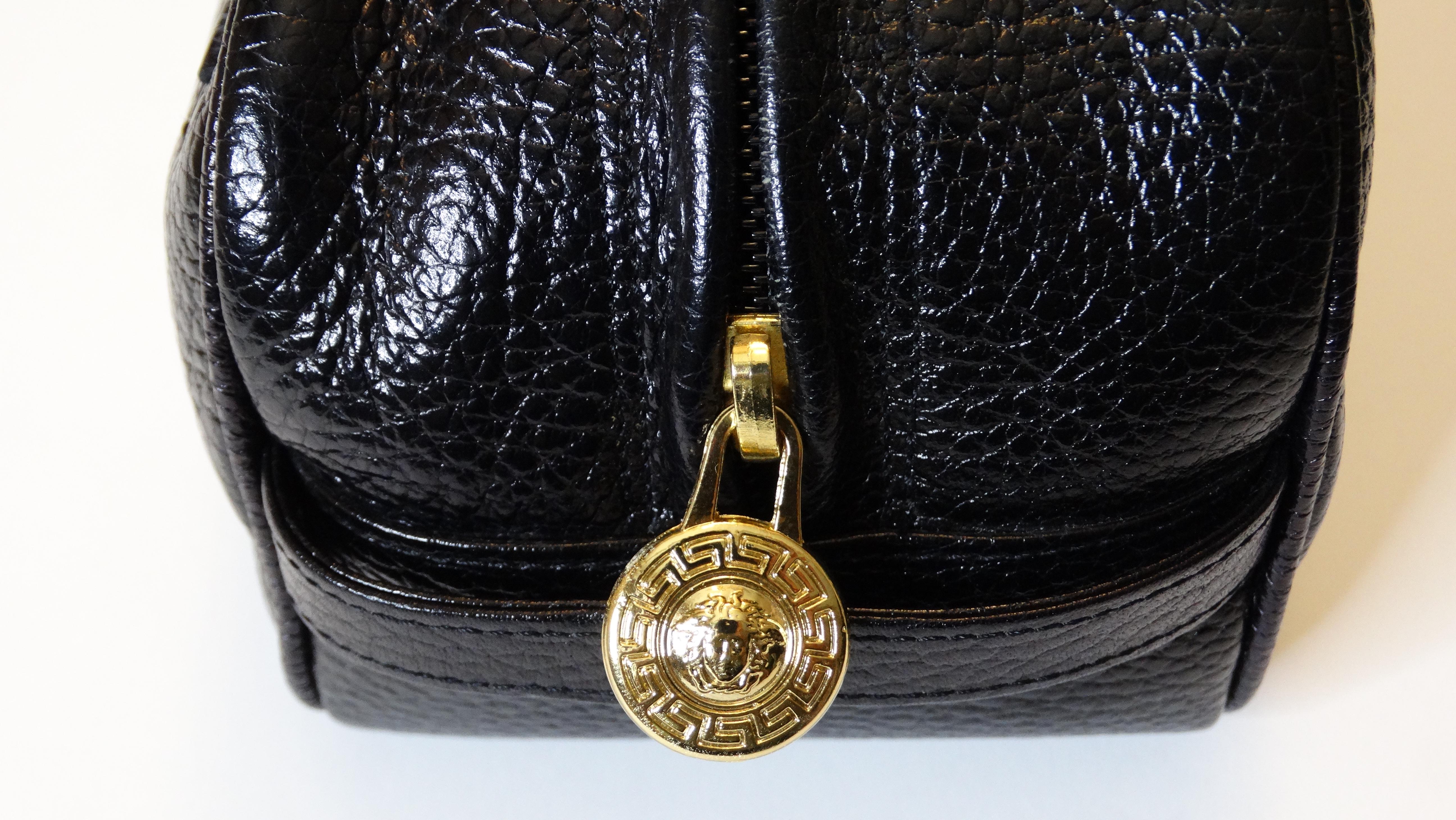 Travel in style with this Gianni Versace cosmetic bag! Circa 1990s, this cosmetic bag/clutch is crafted from black pebbled leather and features the signature Versace Medusa head embossed on the front. Includes two side straps, gold hardware and a