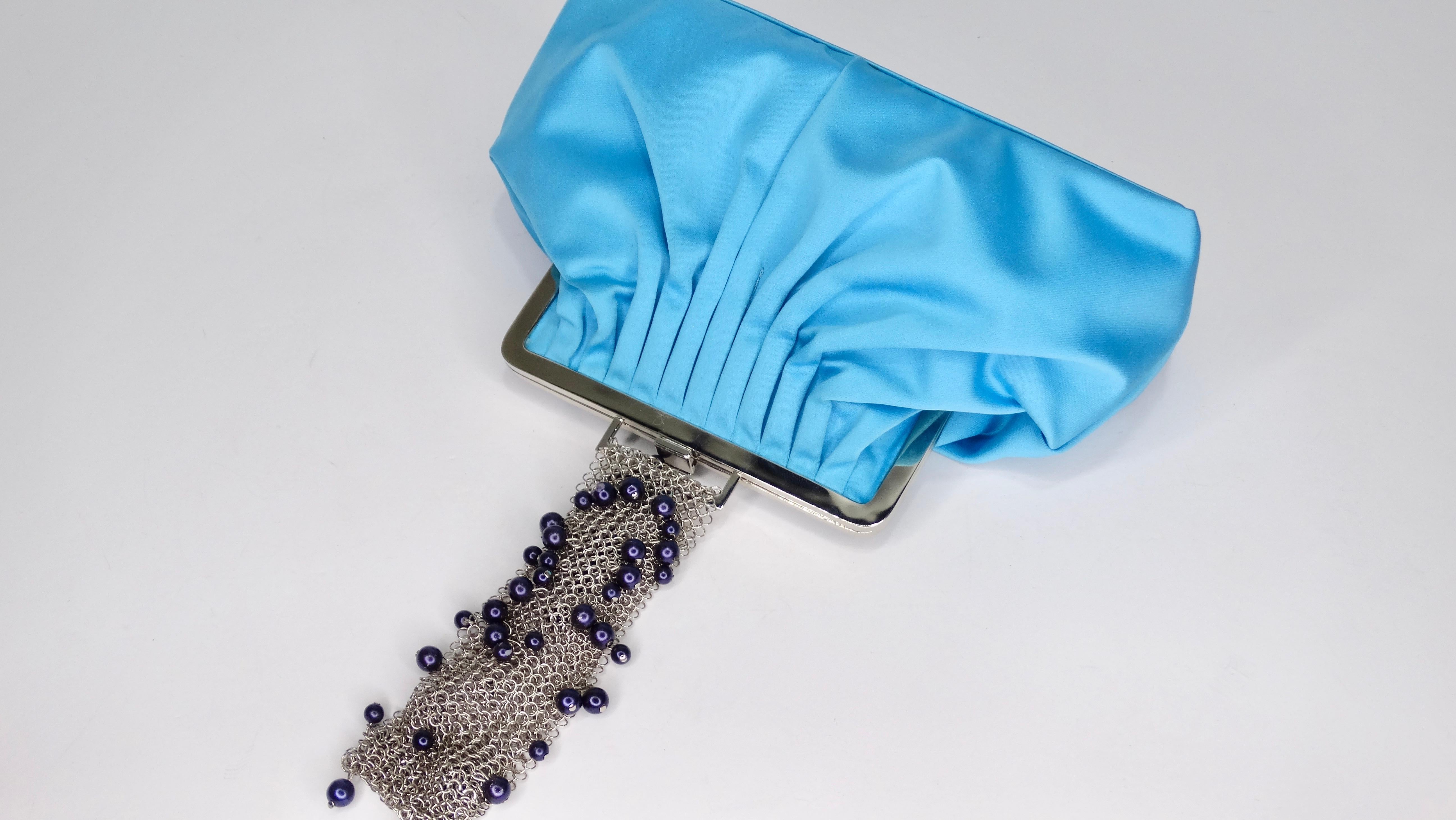 Accessorize in style with this Gianni Versace bag! Circa 1990s, this clutch/wristlet is crafted from aqua blue satin and features pleating at the top, silver hardware, a chainmail wristlet with blue beads, and a Medusa embossed latch closure.