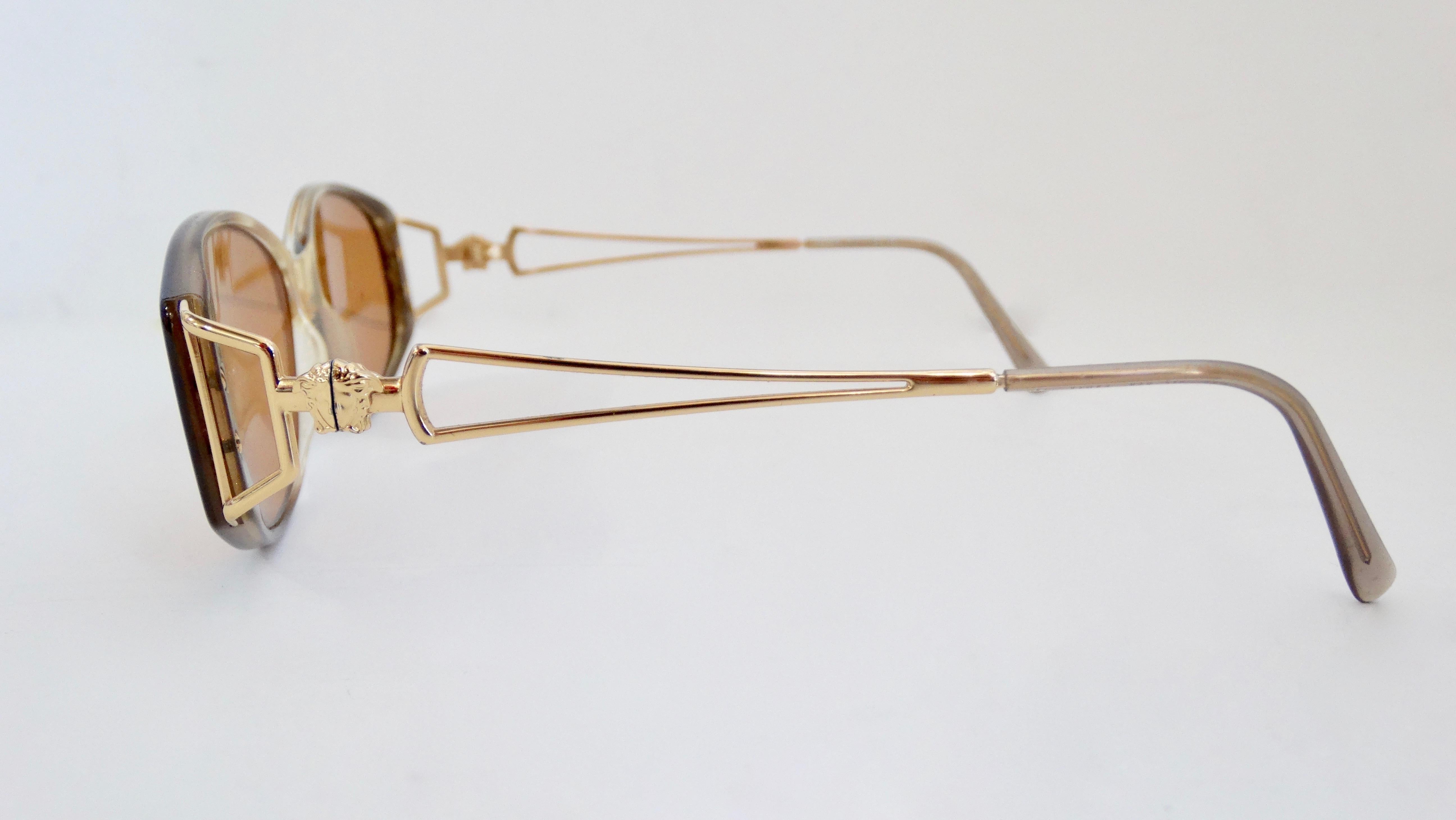Nous avons tous besoin d'une paire de lunettes de soleil Versace ! Datant des années 1990, ces lunettes de soleil présentent une monture ovale avec une finition gradient marron et des verres marron. Les bras minces en plaqué or, avec une petite tête