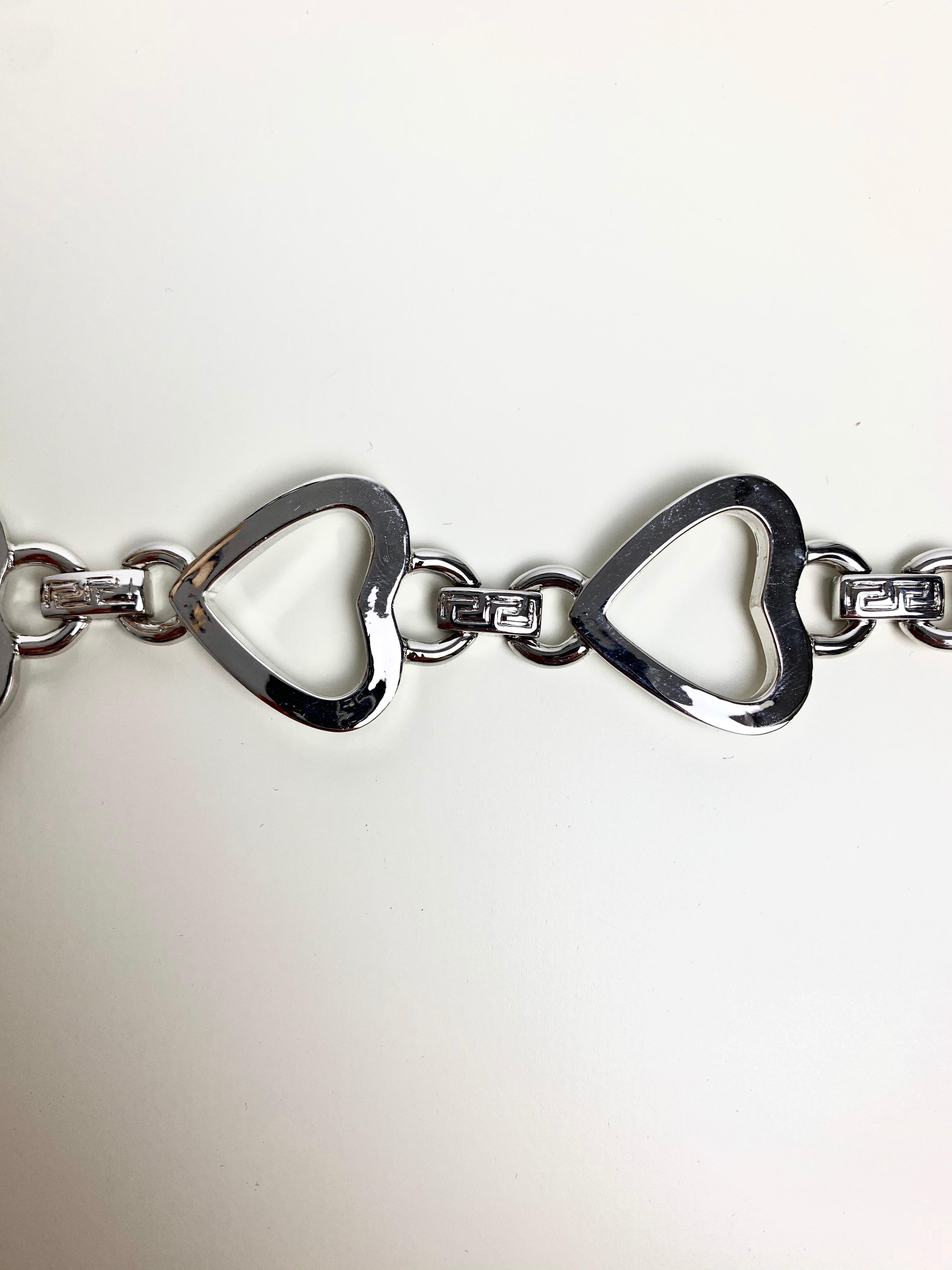 This Gianni Versace silver tone cuff love heart bracelet features a link bracelet made up of four Large love heart motifs. The curb chain features the iconic Greek tile motif and the first live hear has the Versace medusa head in the centre