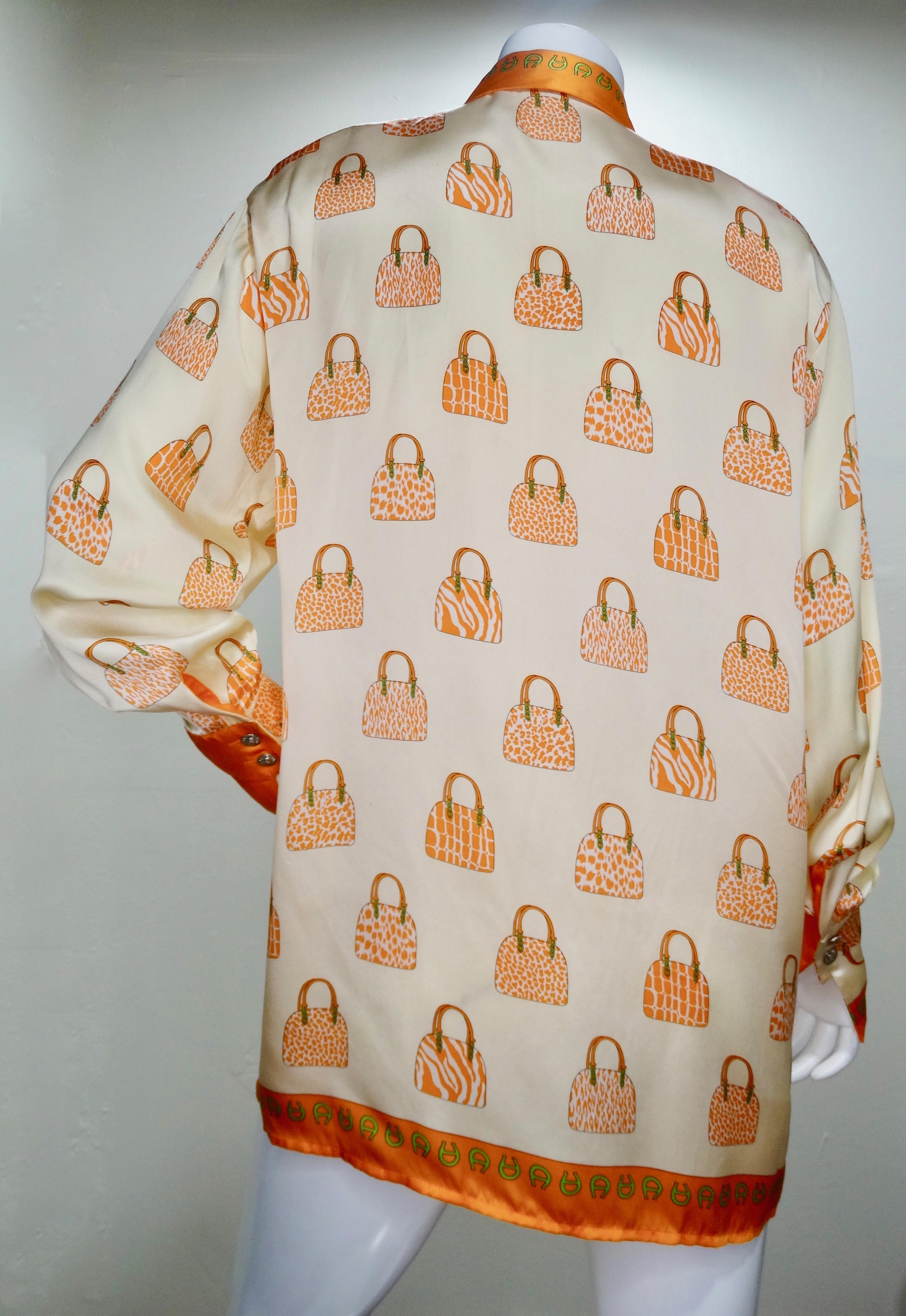 Circa early 1990s, this shiny cream colored Silk button down shirt features a motif detailing handbags with various animal prints. Features an orange trim and strong shoulders. Includes a hidden button down front, traditional collar and embossed V2