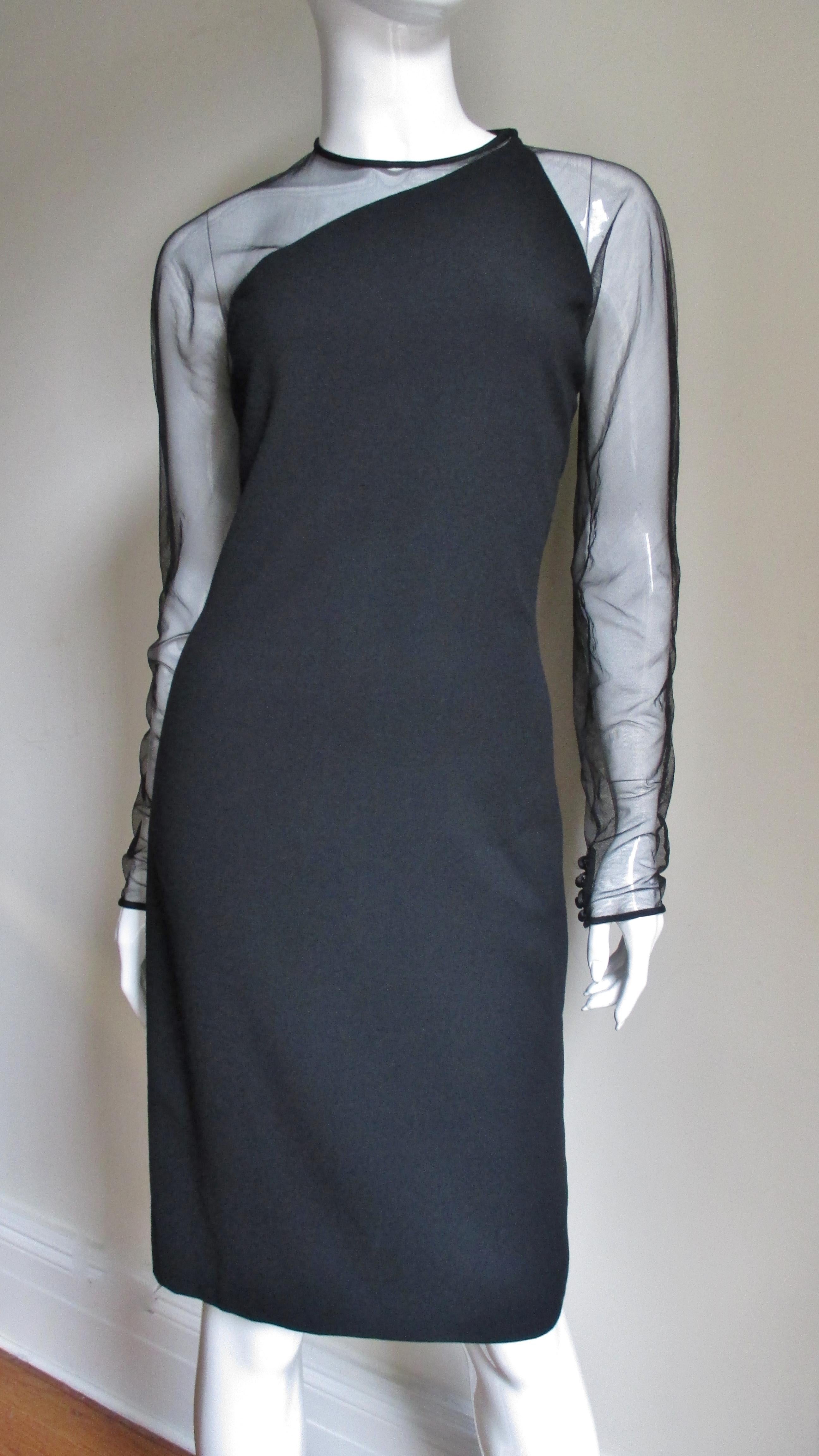 A great black light weight wool and net dress from Gianni Versace Couture.  One shoulder, the low cut asymmetric back and the sleeves are comprised of black mesh.  The body of the dress is light weight wool.  It is fully lined, has a back zipper,
