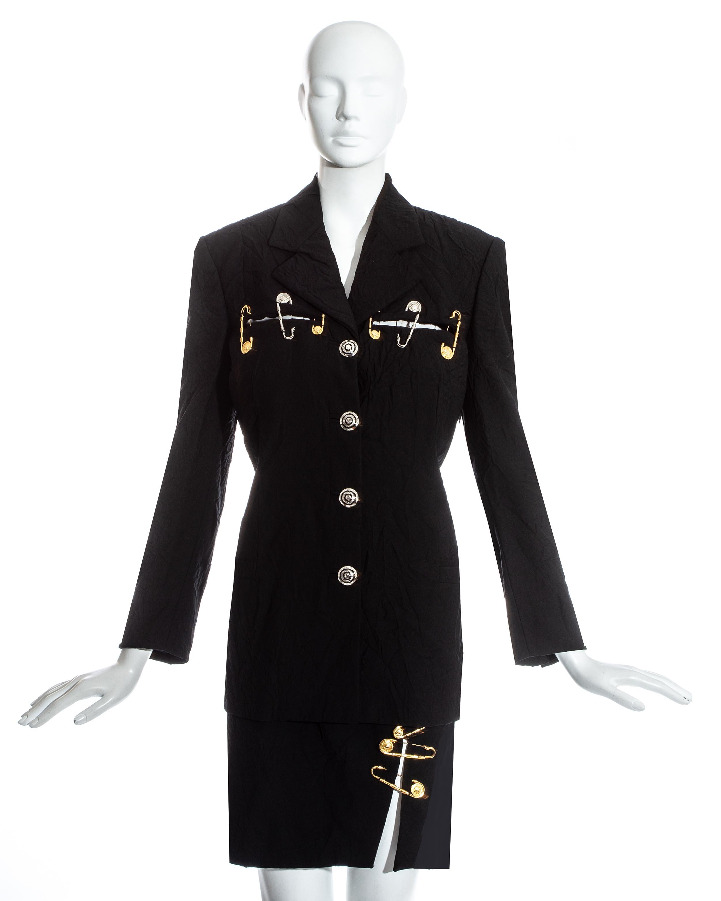 Gianni Versace black crinkled skirt suit. Blazer jacket with slashed cut outs and gold and silver safety pins. High Waisted mini skirt with leg slip held together with three safety pins. The fabric is intentionally permanently crinkled.