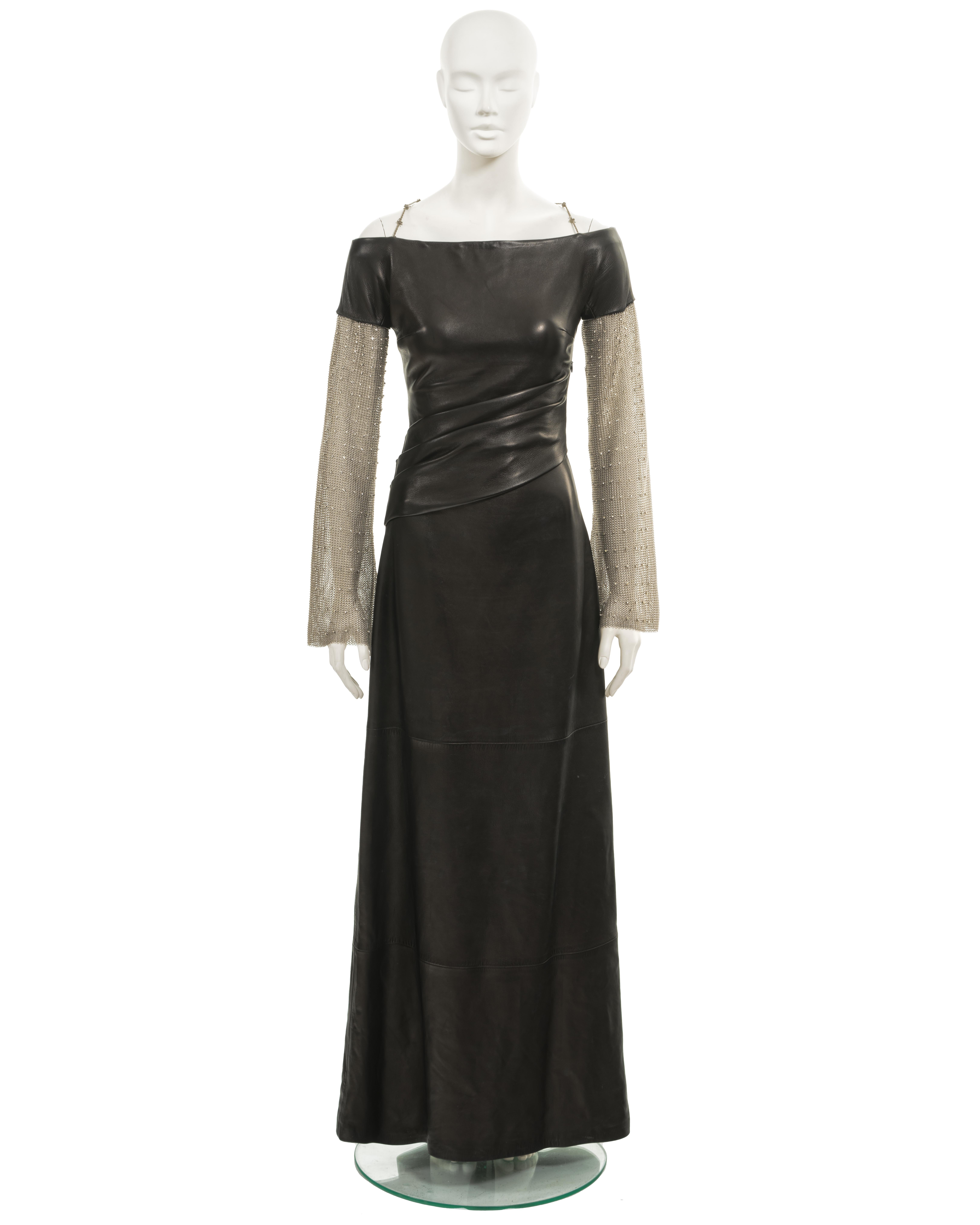 Presenting an archival Gianni Versace evening dress from the fall-winter 1998 collection. This dress is expertly crafted from black leather and exhibits refined design elements.

With a boat neck and floor-length multi-panelled skirt, the dress
