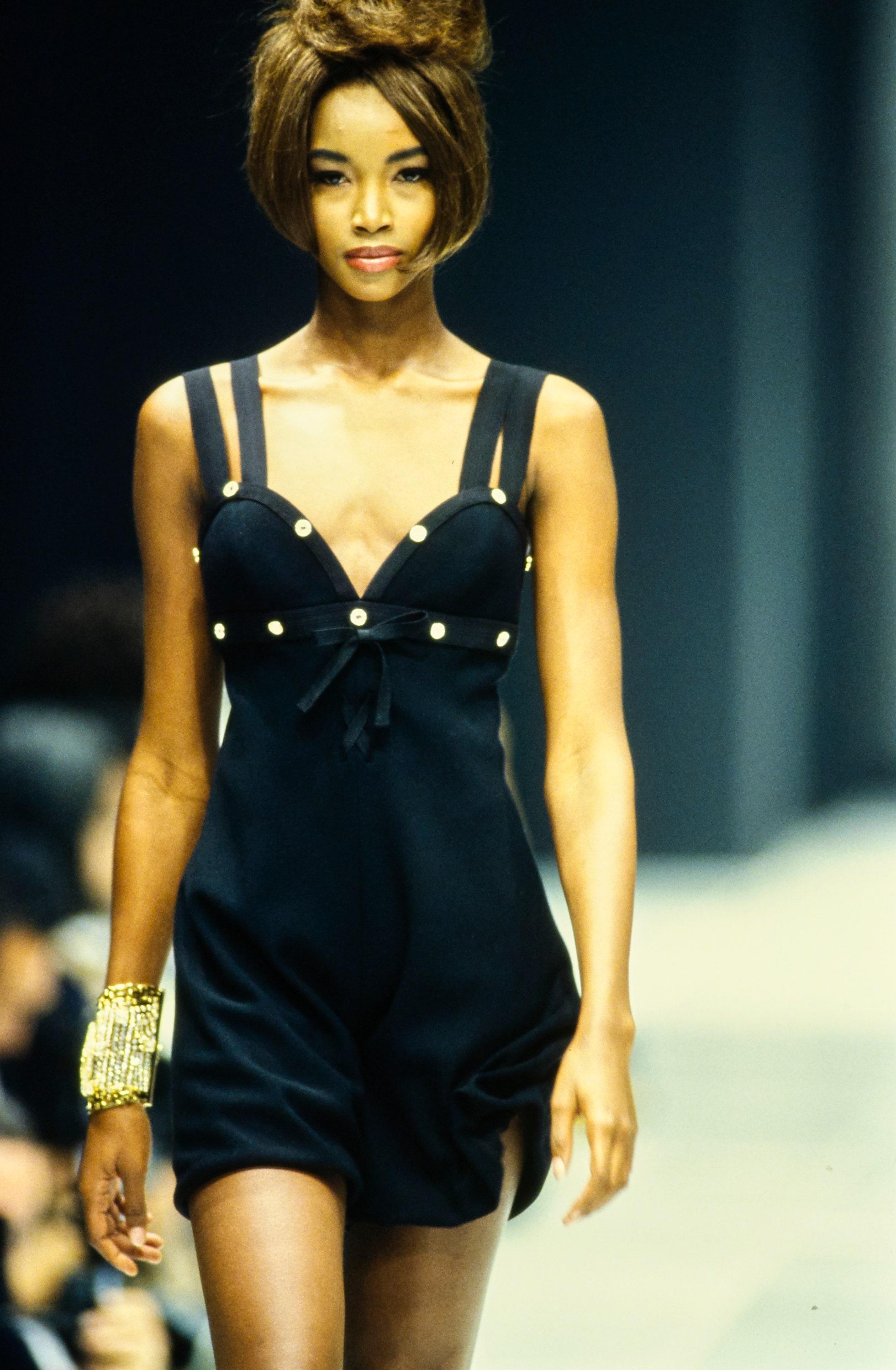 ▪ Gianni Versace black evening playsuit 
▪ Double strap 
▪ Sweetheart neckline 
▪ Bow and criss-cross detail at center-front 
▪ Gold studs with crystals 
▪ 62% Virgin Wool, 38% Silk
▪ IT 38 - FR 34 - UK 6
▪ Spring-Summer 1992
