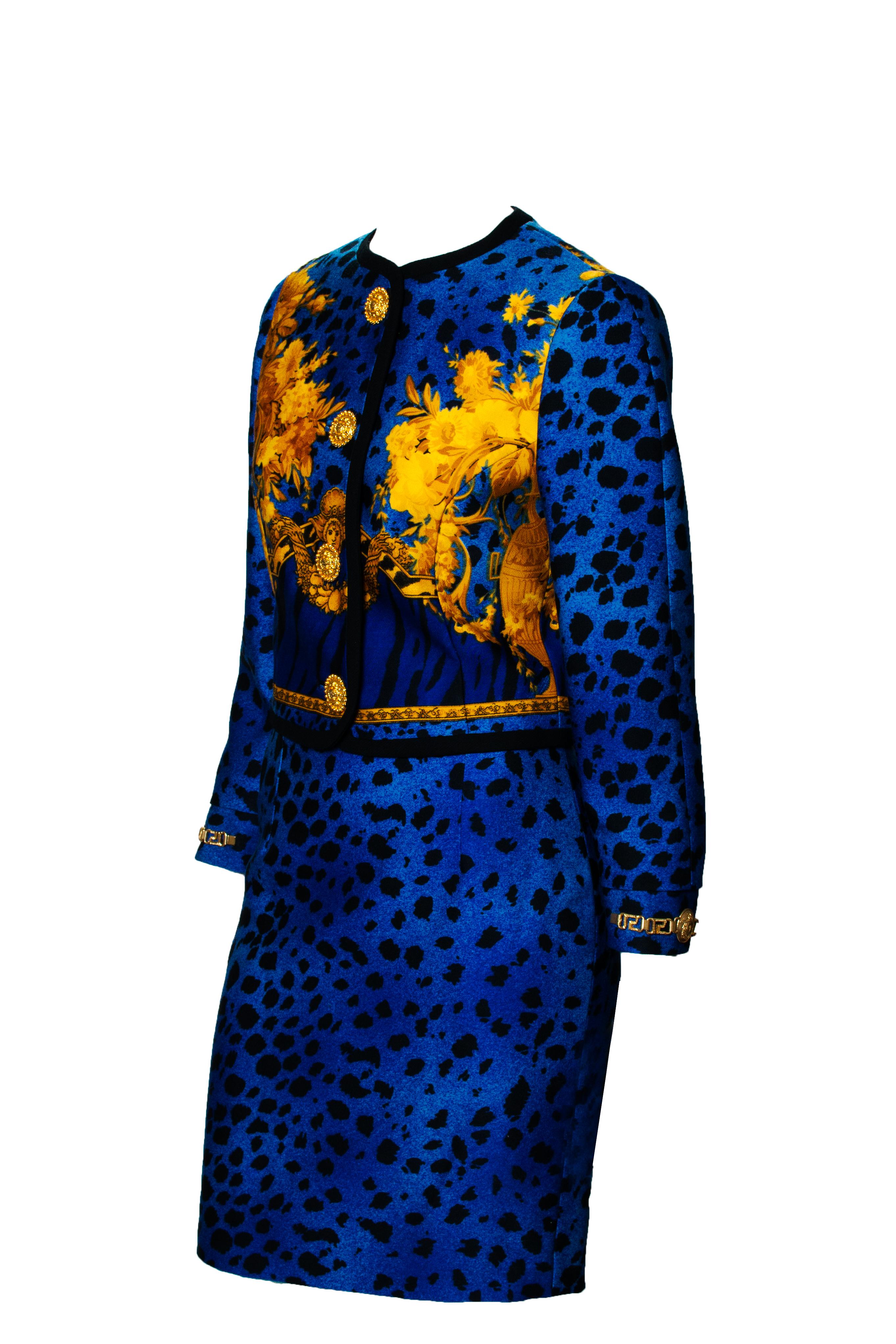 From 1992, this Gianni Versace skirt suit features a bright blue leopard print throughout. There is a blue tiger print section on the front and back next to a golden baroque pattern. Large gold-colored Medusa buttons are highlighted on the front of