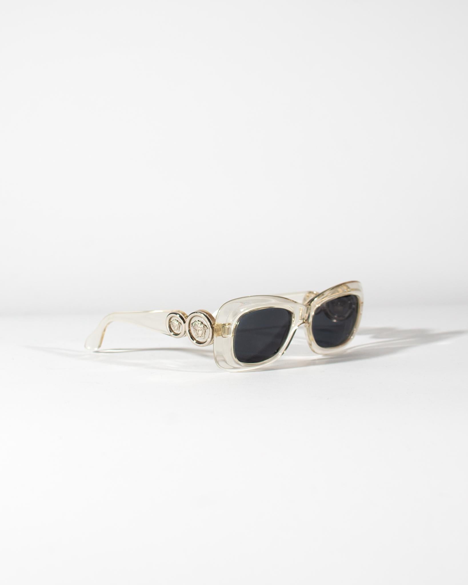 Presenting These translucent, vintage Gianni Versace glasses have an oval shape with a slight tilt creating a cat-eye shape. The arms have two round silver Versace Medusa emblems on each side. The model is similar to the house's iconic 'Biggie'
