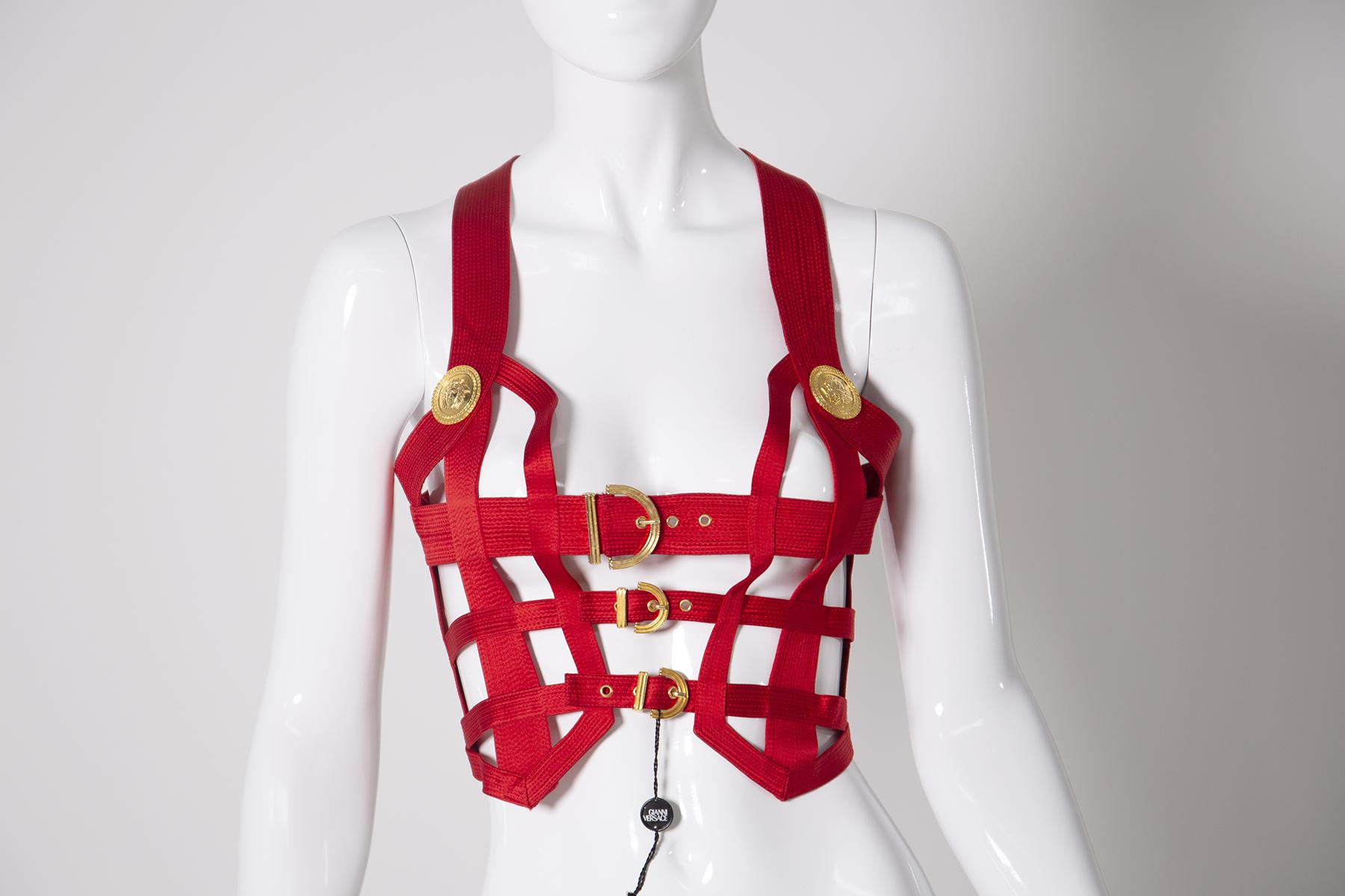 Incroyable, iconique et très rare corset cousu en soie rouge par Gianni Versace Couture avec corsage bondage en soie rouge avec garniture gaufrée Méduse en or. Labellisé avec une taille italienne 42 qui correspond à un US 2 ou 4.Fabriqué en Italie.