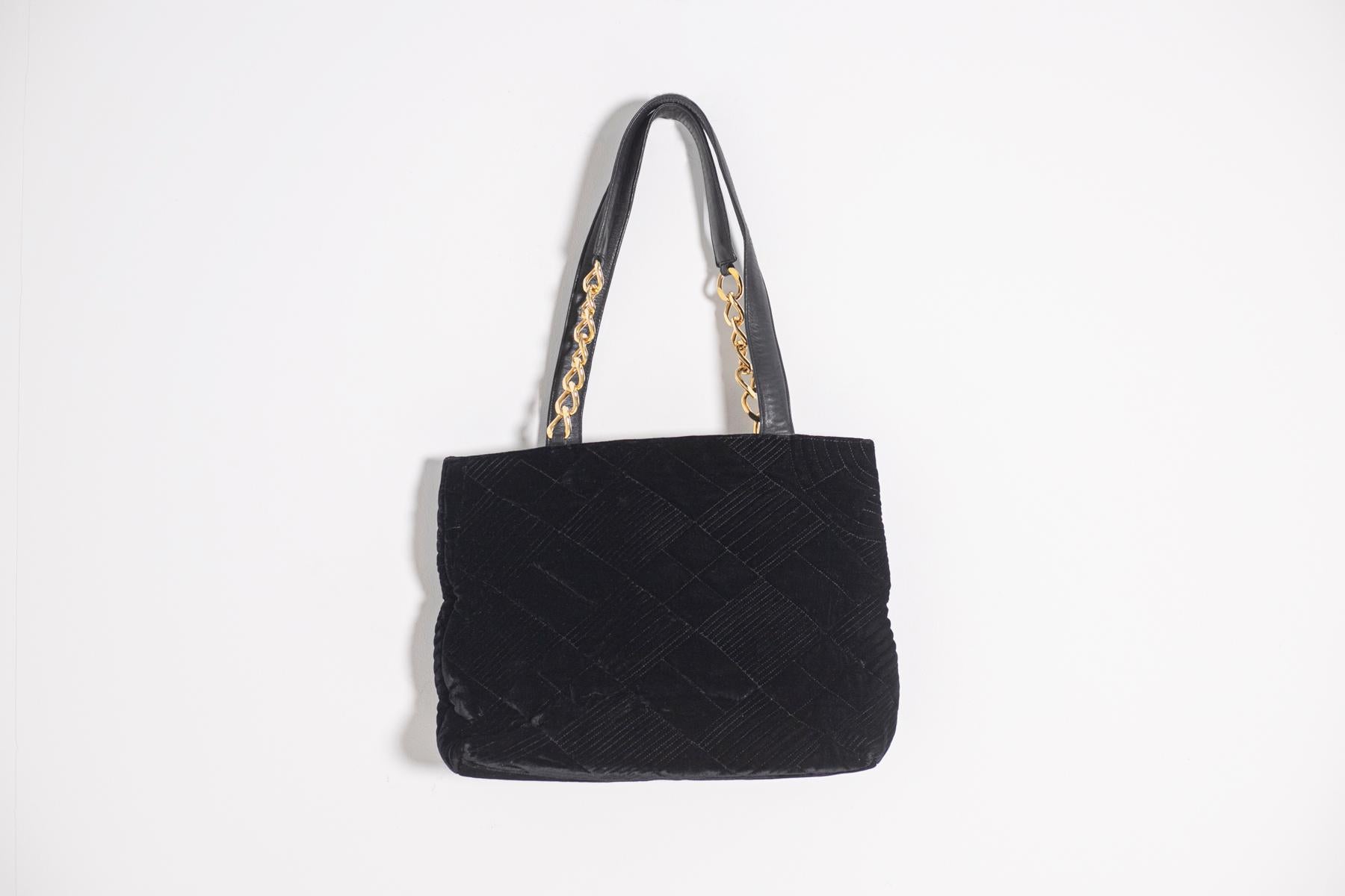 Beautiful black velvet tote bag signed Gianni Versace Couture 1990s.
The outside of the bag is made of black velvet worked, two long and particular handles in very soft black leather that are attached to the bag by a golden metal ringed chain. It is