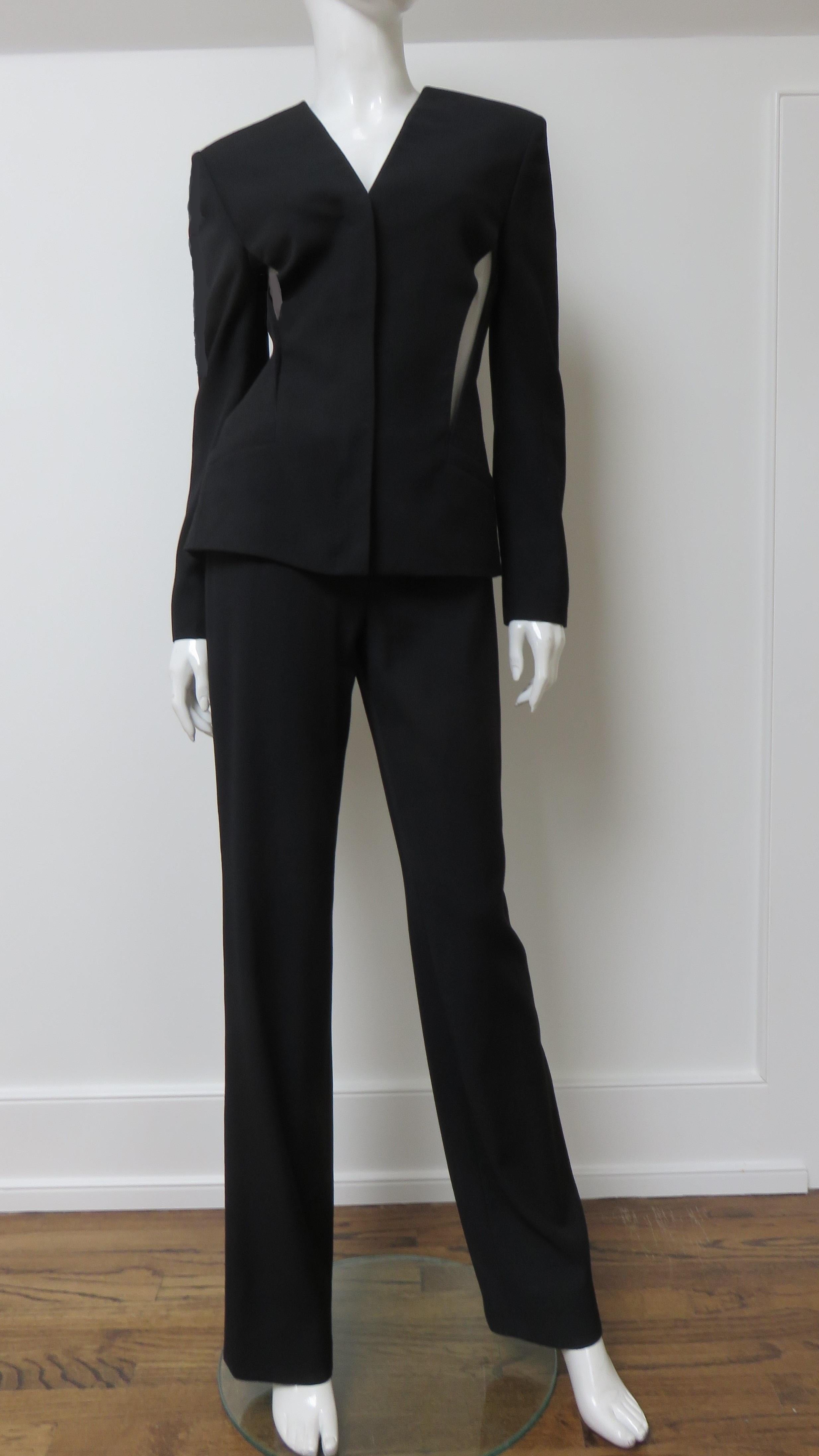 A gorgeous black silk pant suit from Gianni Versace Couture. The jacket has a V neckline, princess seaming for a flattering fit, lightly padded shoulders, a front zipper closing, and a mesh covered wedge cut out from underarm to pocket on each side.