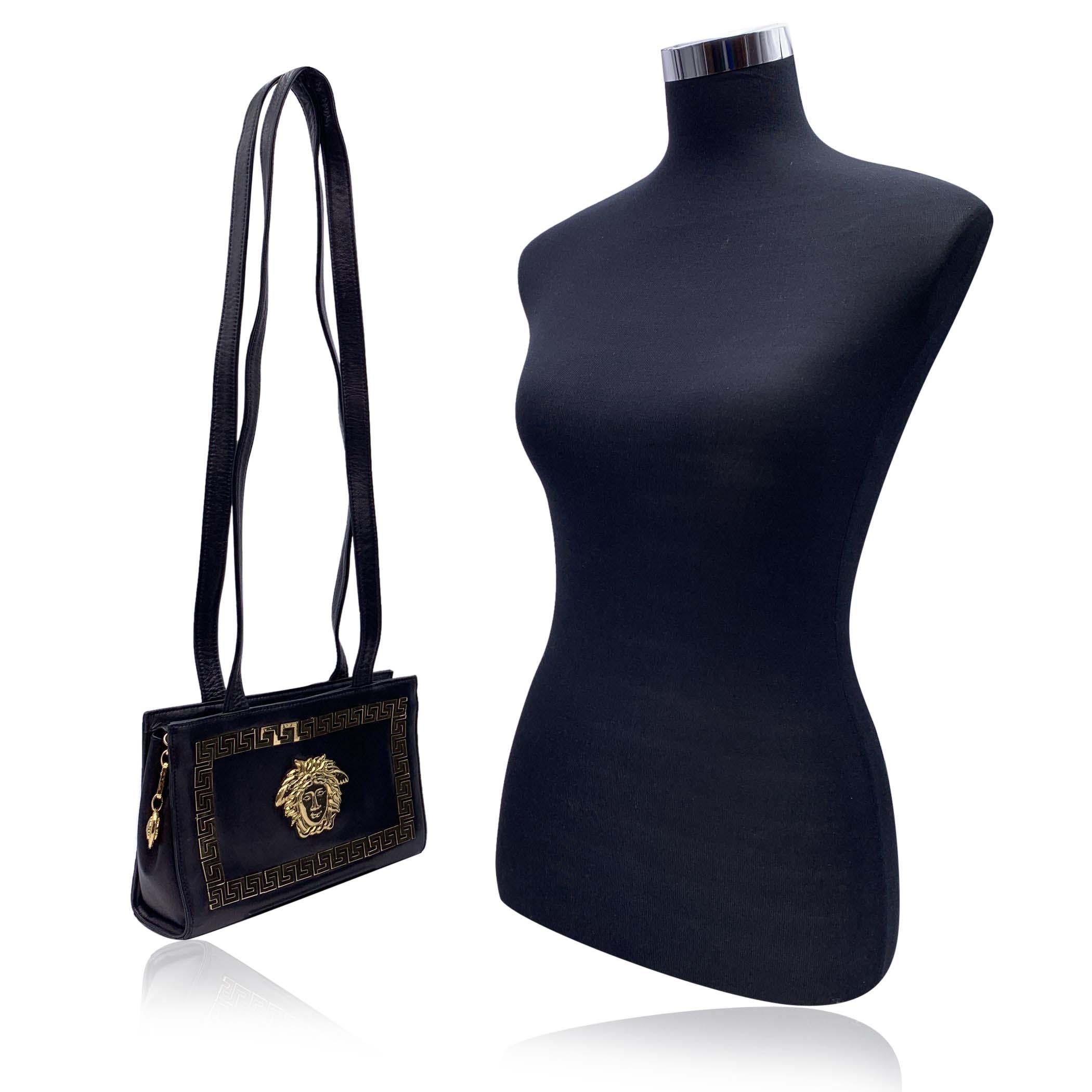 Magnifique sac à bandoulière vintage Gianni Versace Couture des années 1990. Réalisé en cuir noir, il est orné d'un grand logo Medusa en métal doré sur le devant et de bordures en forme de clé grecque. Longues bretelles. Fermeture à glissière sur le