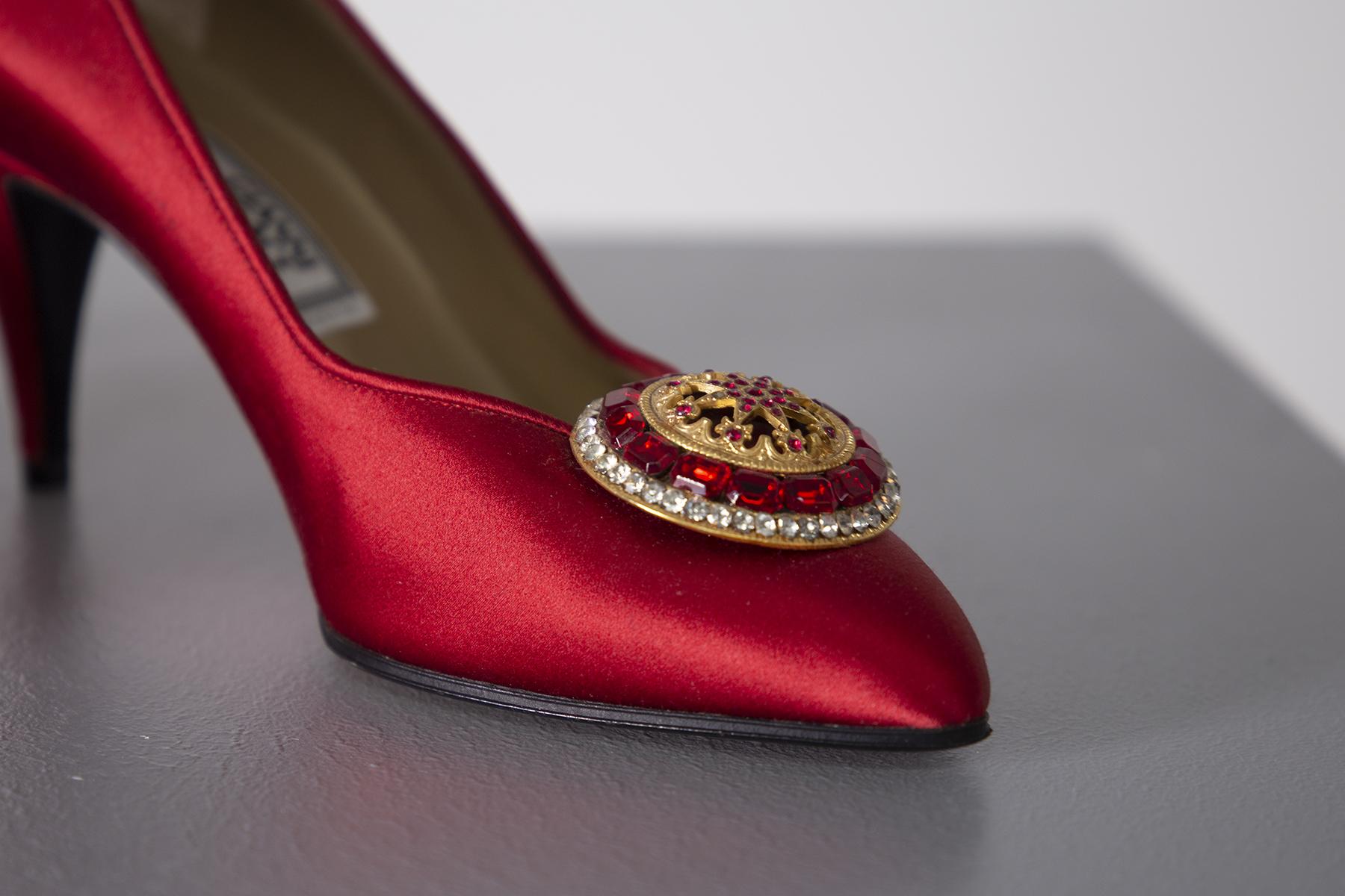 Stunning pair of Gianni Versace decolletè from the 90s. Exceptionally designed and made wonderfully detailed. Gianni Versace's label inside the shoe. The heel measures 7 cm. The shoes are in red satin fabric. The tiara is made of gold metal framed