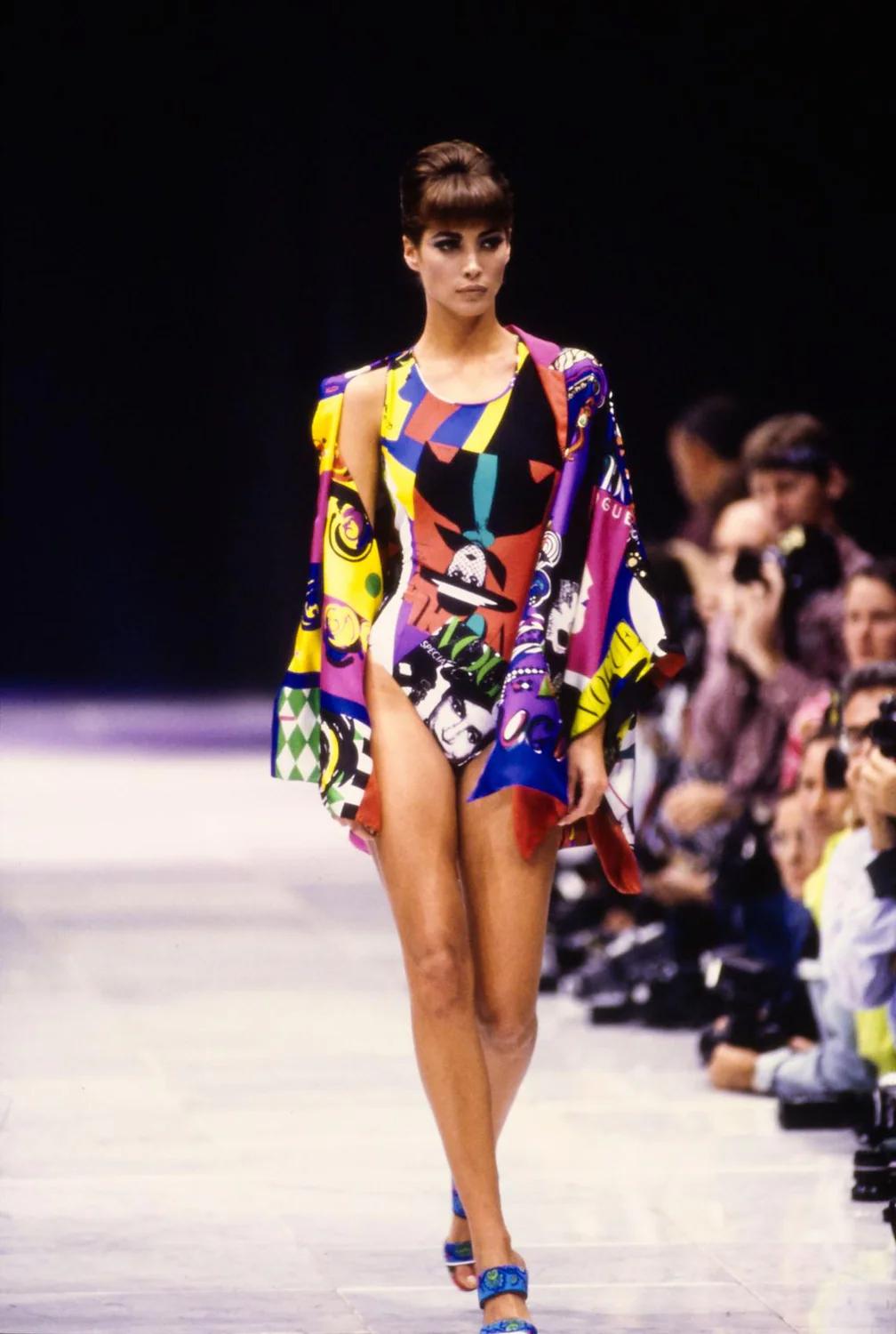 Gianni Versace Couture Vogue Shirt is a rare piece from the Spring Summer 1991 collection featuring the iconic all over Vogue print, an oversized blouse with jewelled gold buttons, three-quarter sleeves with lapels, and a v-neckline with a stiff